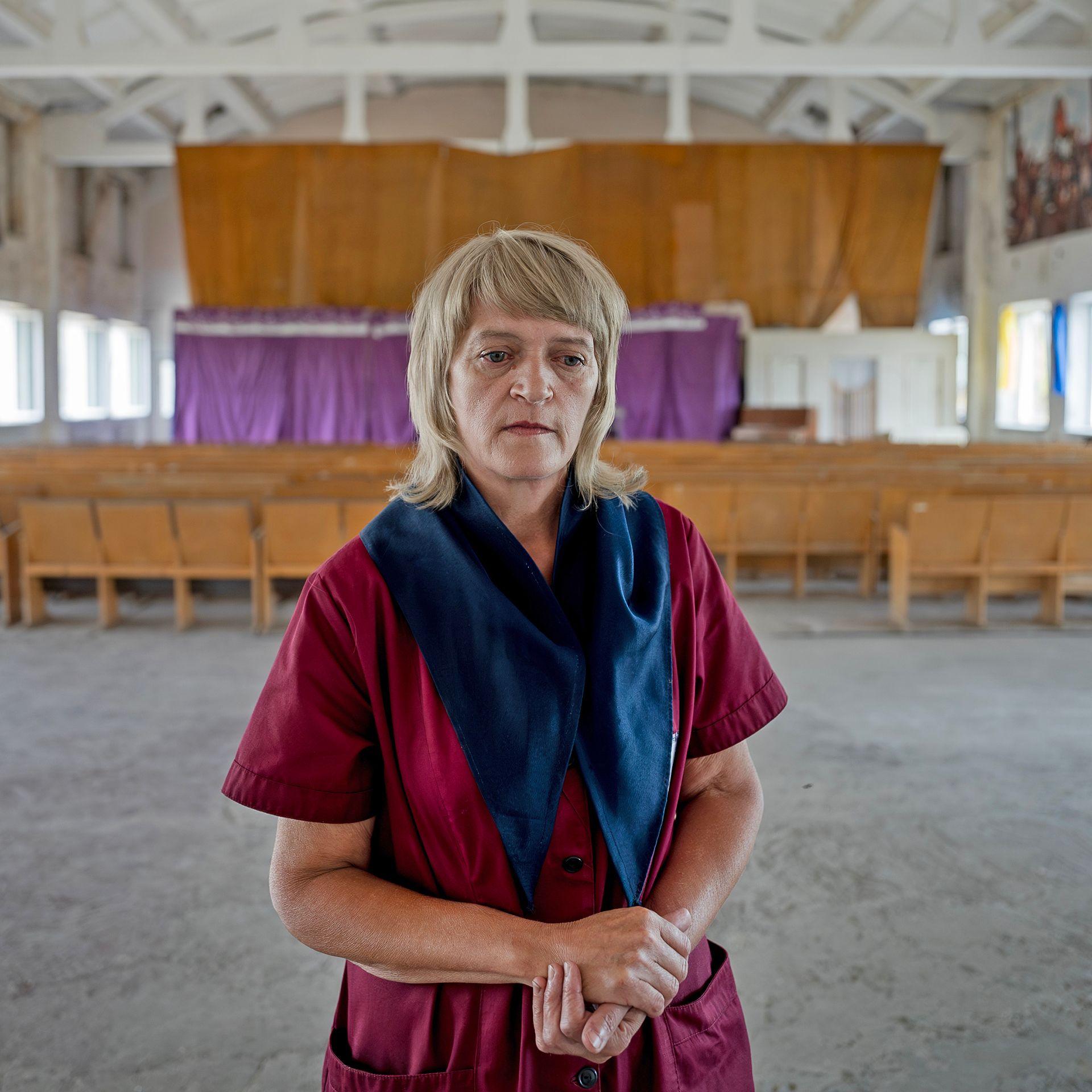 In a large hall within the prison, Tetyana Potapenko looks pensive in her maroon prison overalls