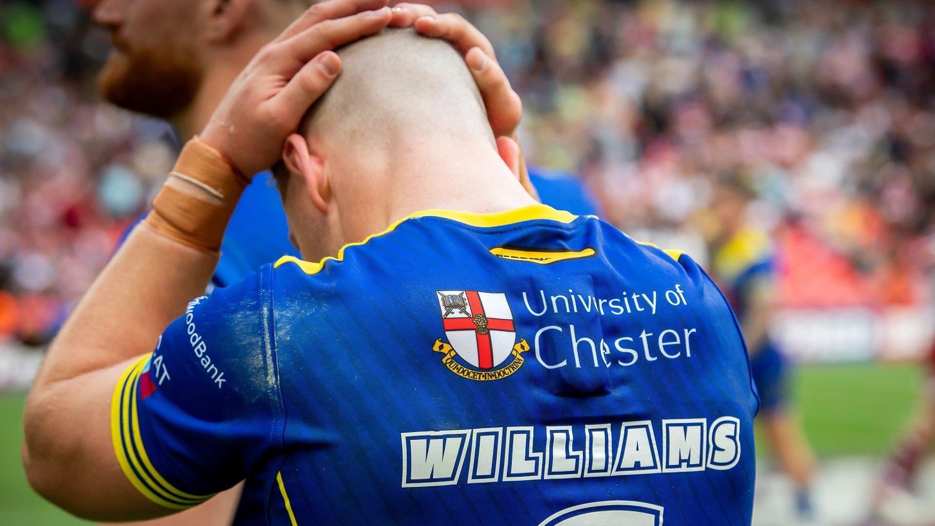 George Williams photographed from behind has his hands on his head in disappointment after Warrington Wolves failed to perform in the 2024 Challenge Cup final against former club Wigan Warriors.