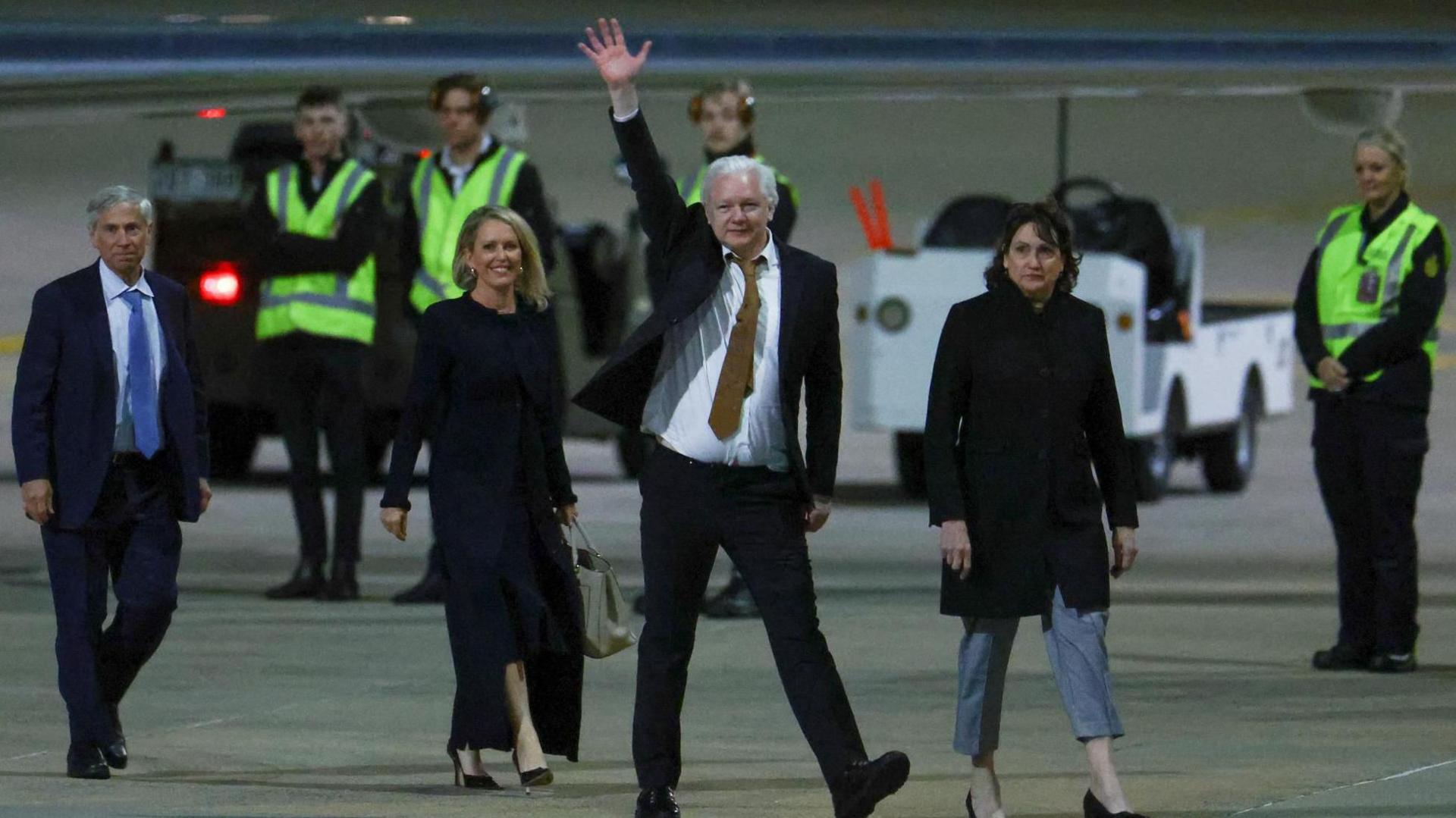 Julian Assange waving on the tarmac at Canberra airport