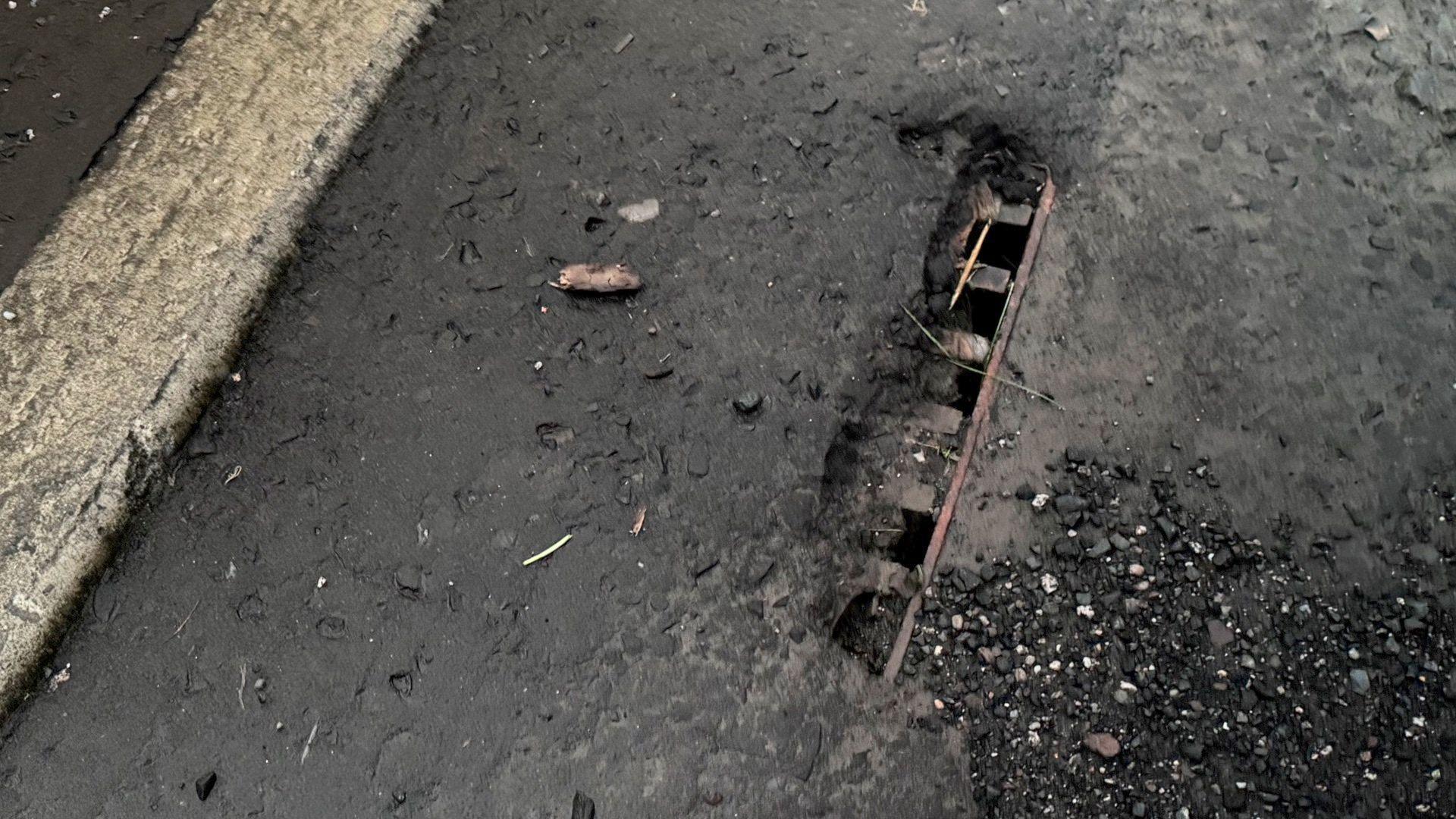 Part of a grating with tarmac over it in Kildrum