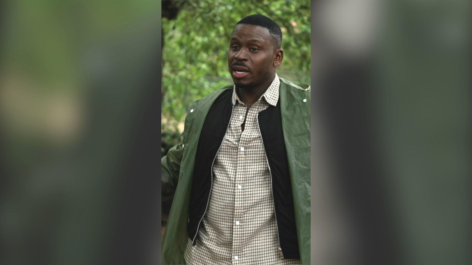 Fekky stands among trees wearing a green jacket. He has short black hair.