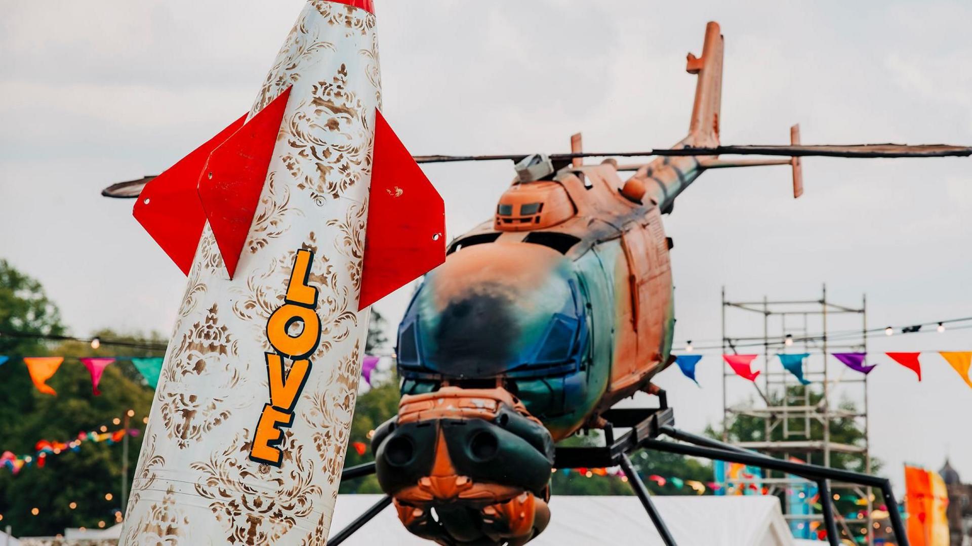 Art installations - one shaped a bit like a rocket with love written on it, another an adapted painted helicopter made to look like a giant fly .