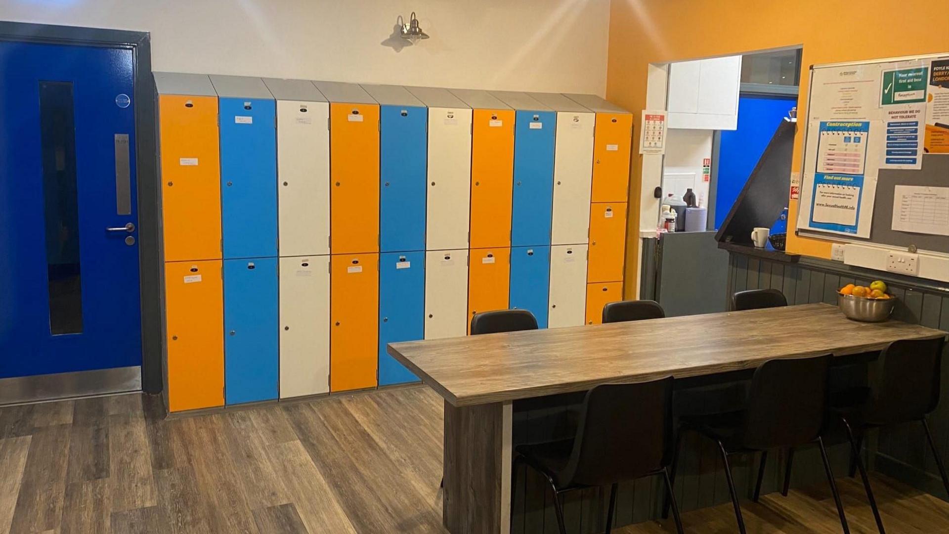 Colourful lockers and a table with a bench. 