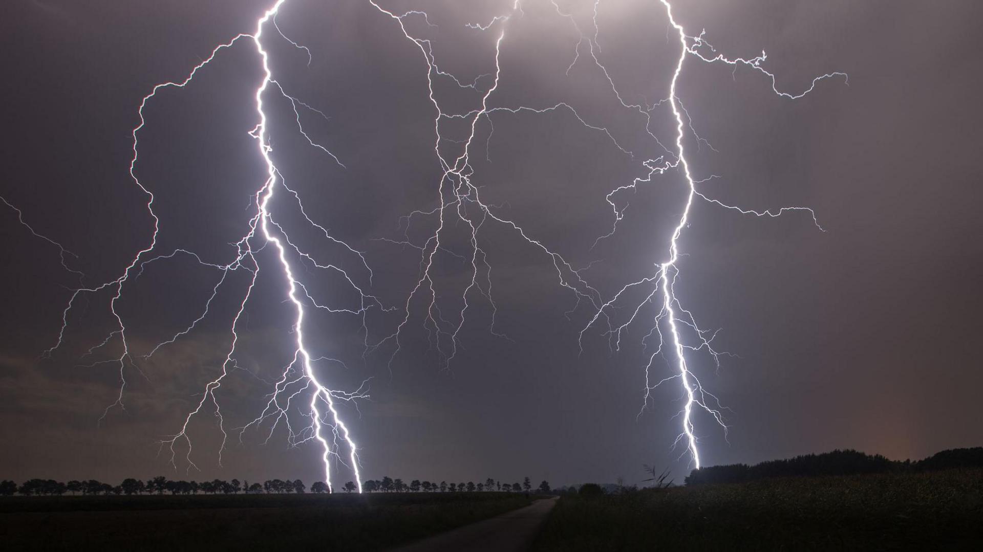 Two large strikes of lightning flash in the grey sky