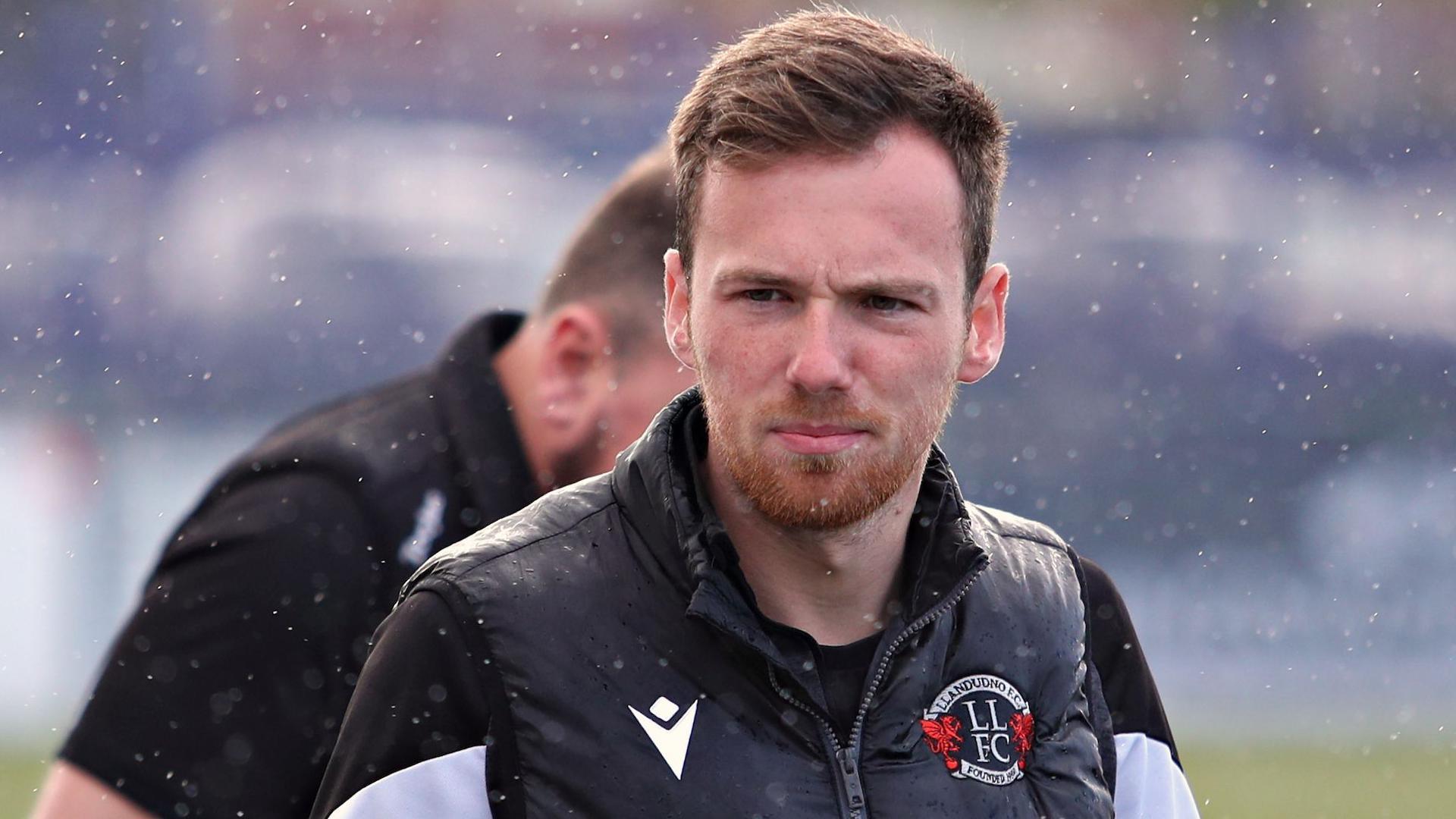 Llandudno manager Jordan Hadaway pictured on the touchline in the rain