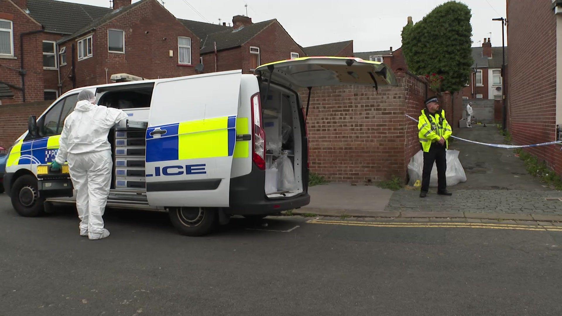 Police at the scene in Doncaster following a man's death on Thursday morning. A forensics officer is taking an item from a police van, with a PC guarding an alleyway. 