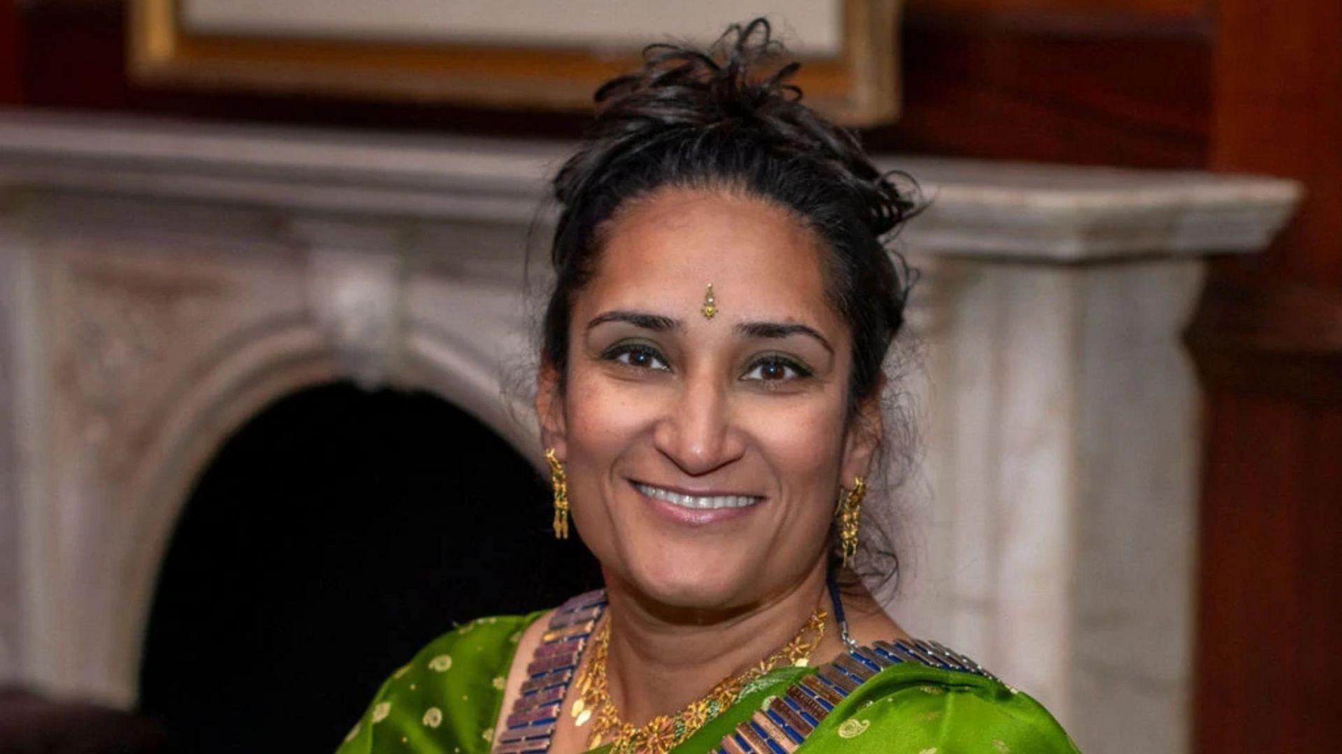 A woman wearing a green sari while smiling at the camera