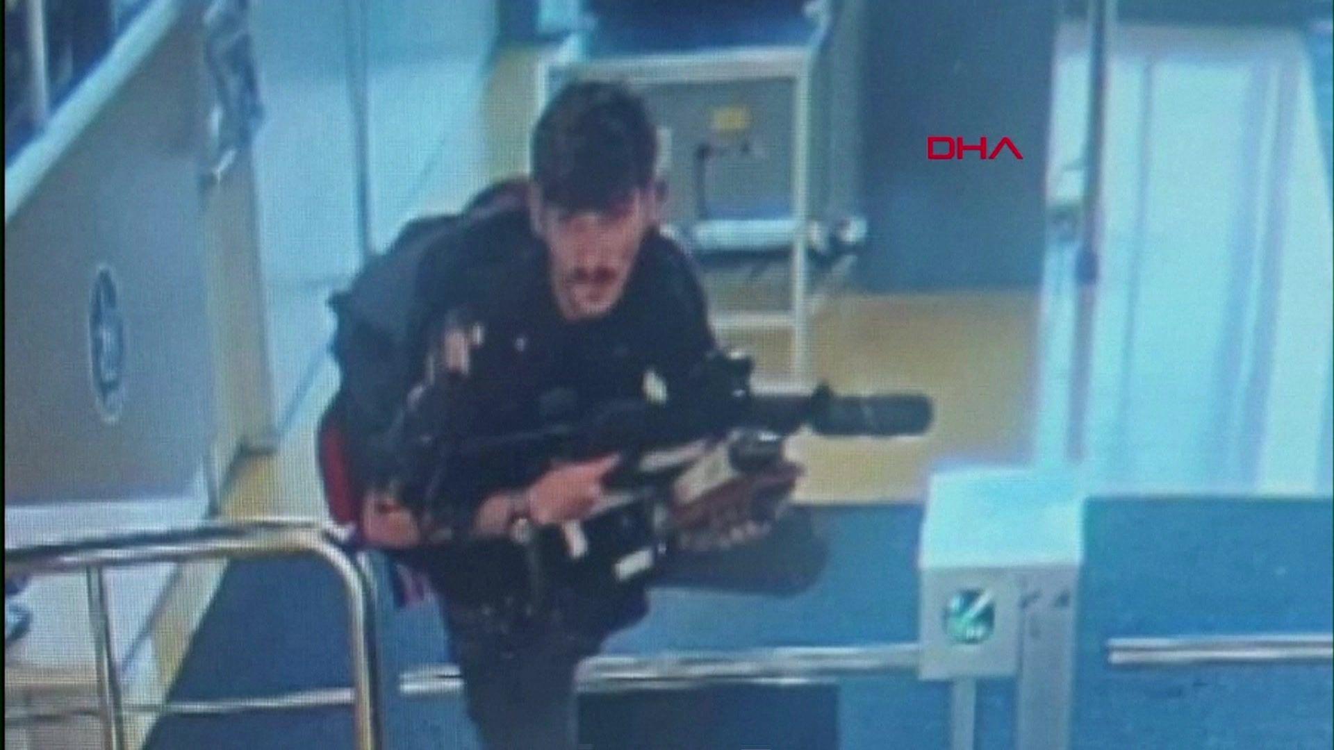 One of the suspects pictured on CCTV climbing over a turnstile holding a gun at the entrance of Turkish Aerospace Industries' headquarters