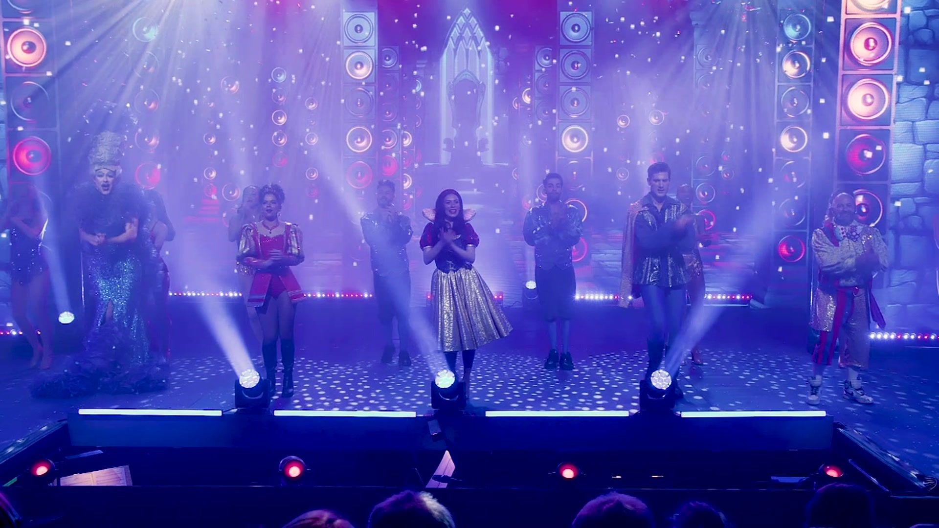 A stage with blue lighting and about ten actors dressed as characters from Snow White, including Snow White in the middle and the dame on the far left 