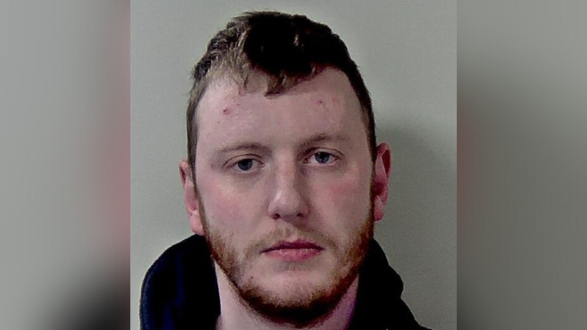 A mugshot of a man with short hair and a beard.