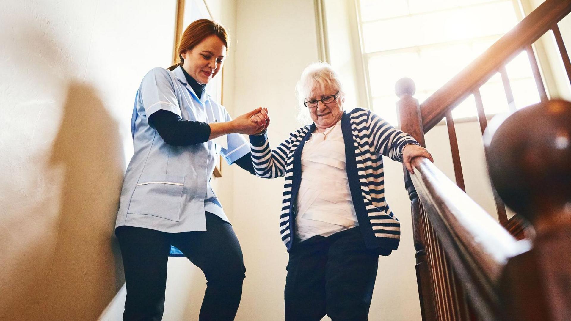 Carer helping a woman down the stairs