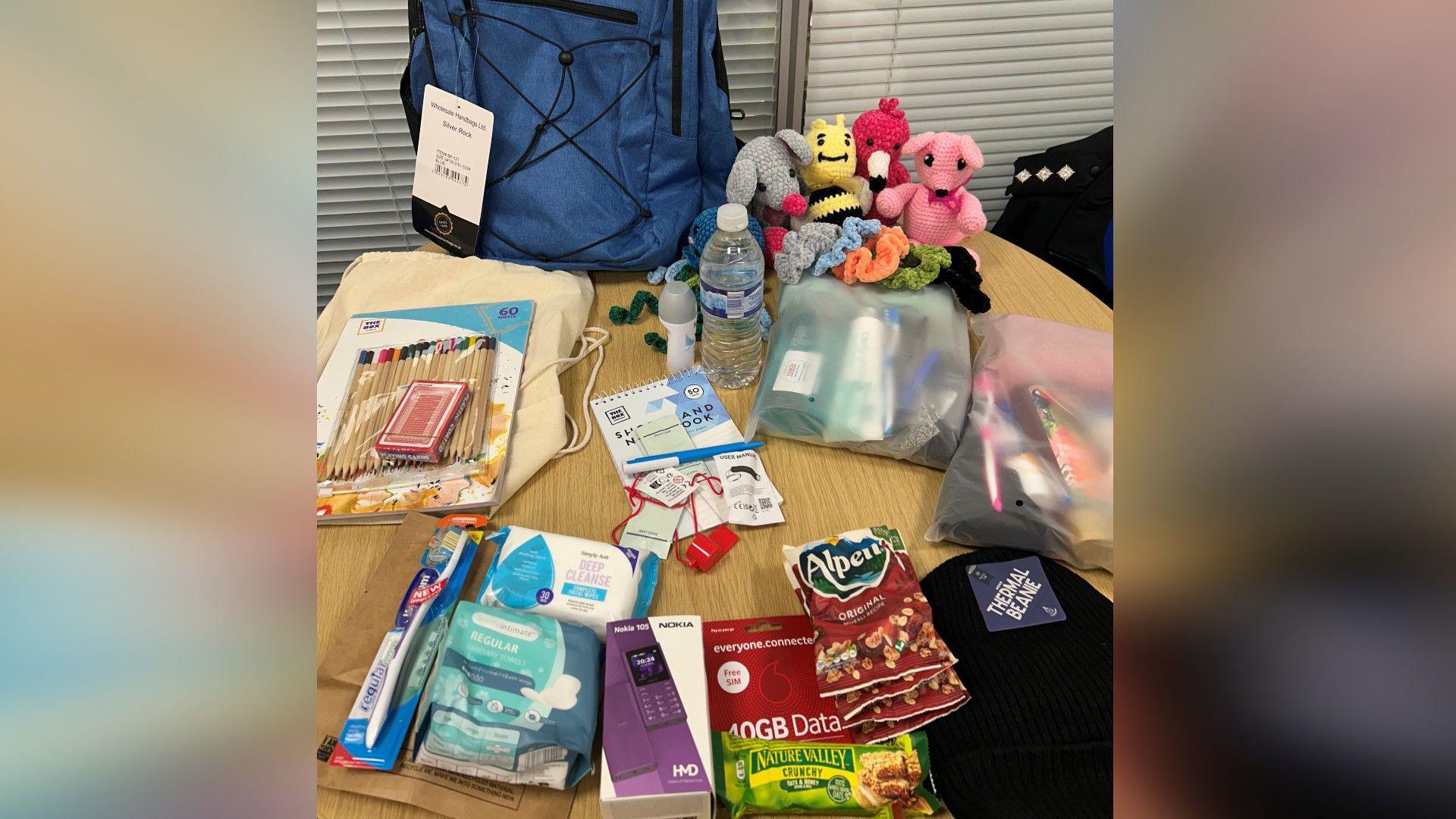 A table with essential items including dental kits, snacks and colouring packs and a blue grab bag.
