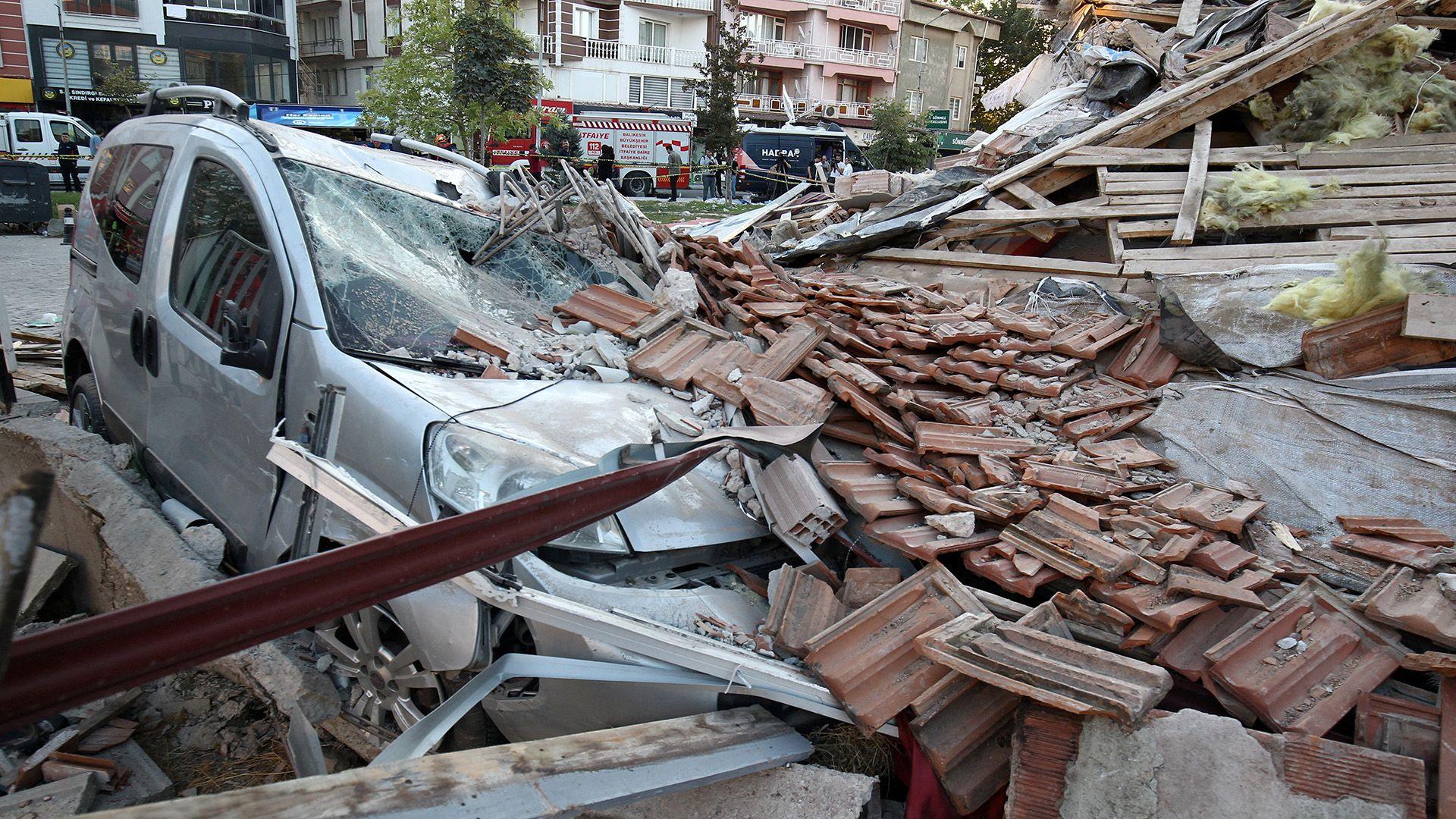 A damaged vehicle lies under the rubble of a collapsed building after an earthquake