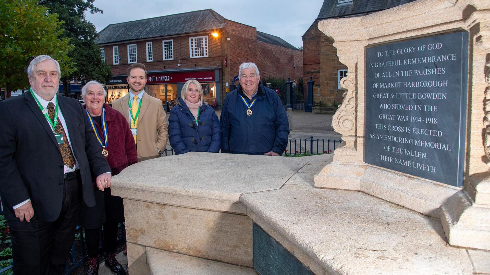 A group of five people are standing to the left of the new slate plaque at the war memorial