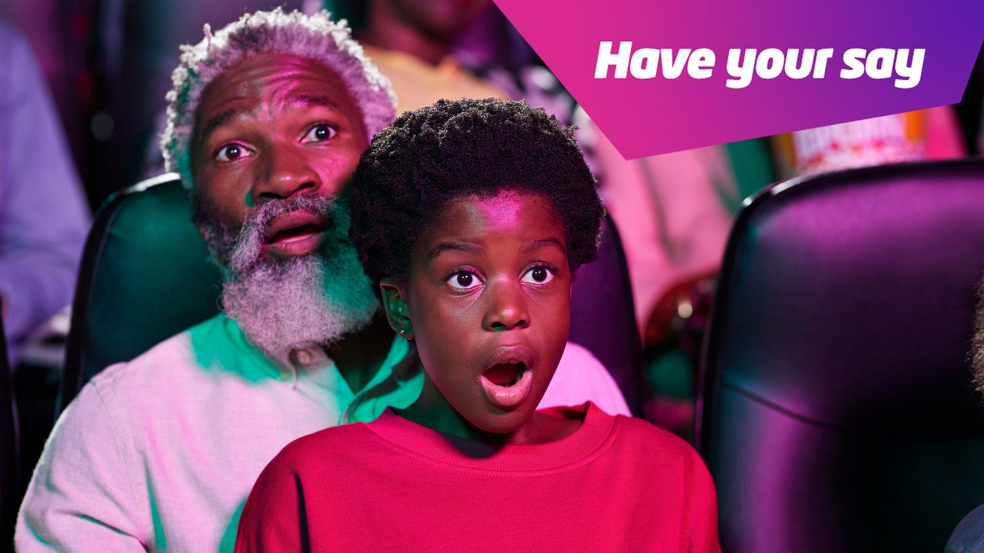 a child sitting on their grandfather's knee shocked watching a movie.