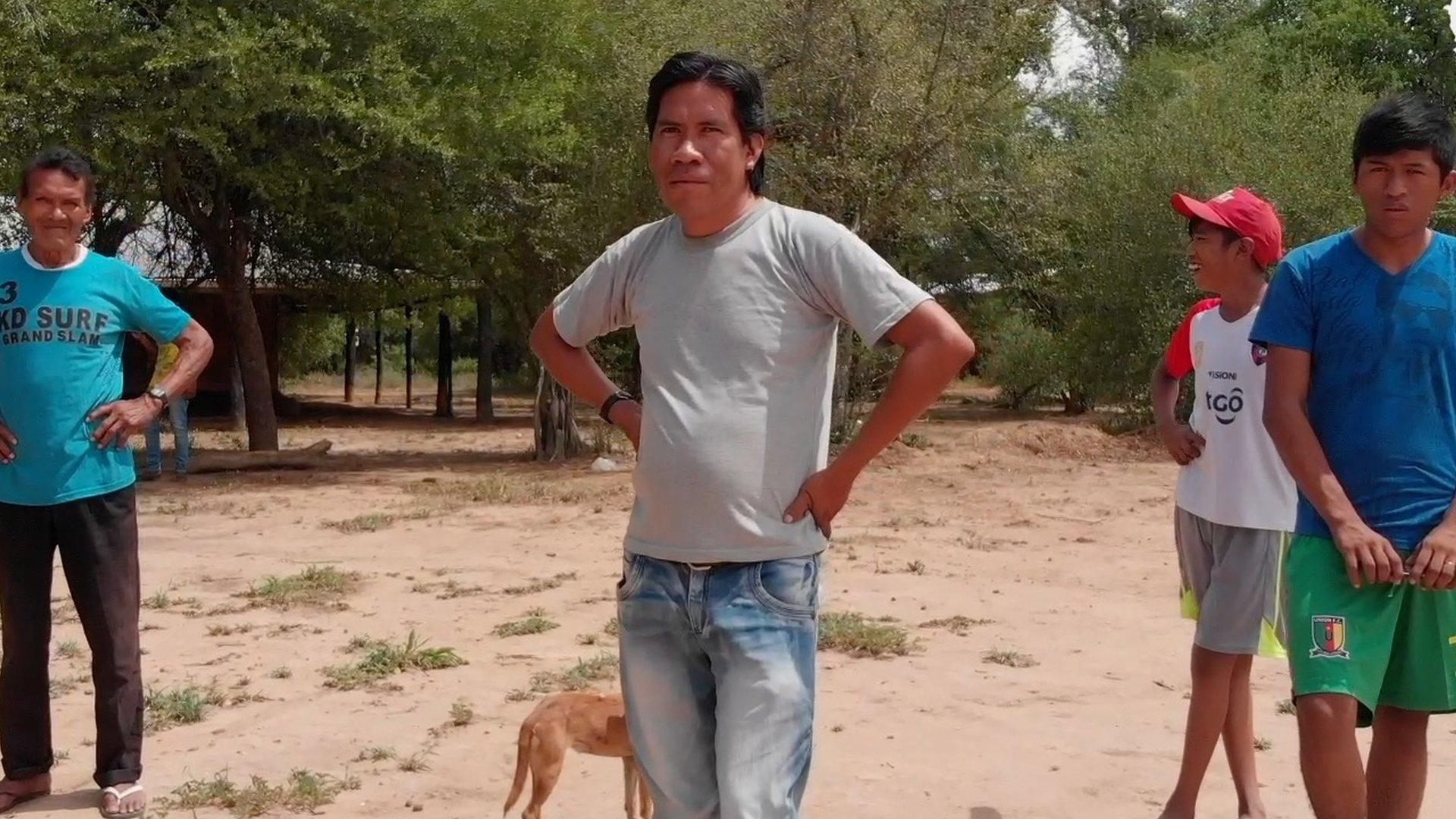 Chagabi standing in the his village with other Ayoreo Totobiegosode members