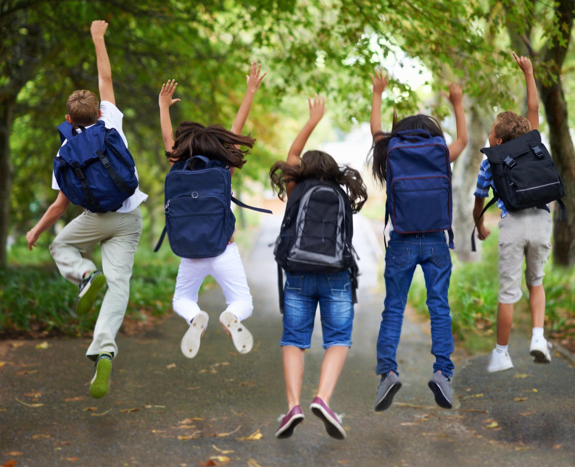 children with backpacks jumping