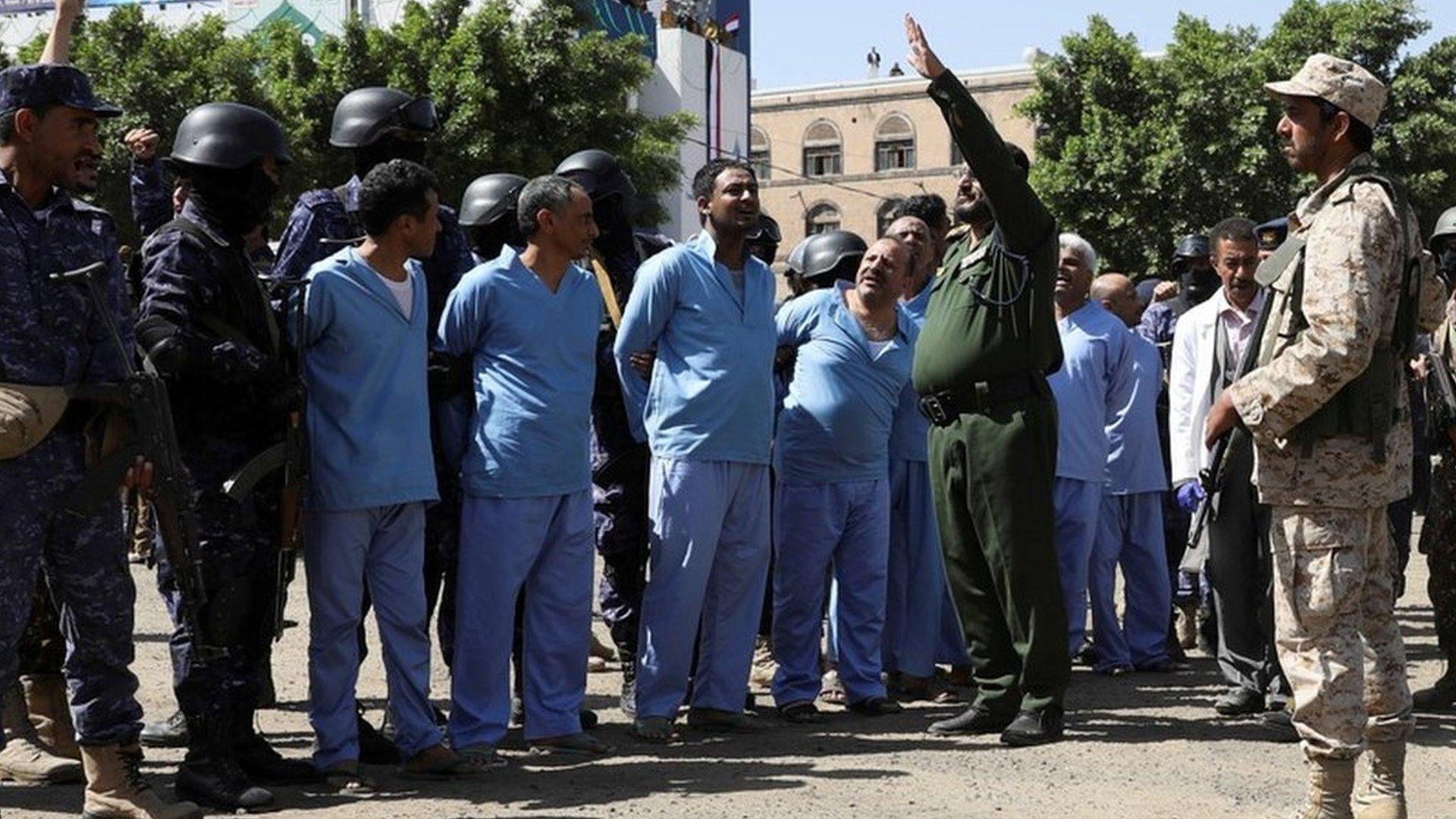 Houthi military personnel stand next to men accused of involvement in the killing of a rebel leader the day before their execution by firing squad in Sanaa, Yemen (19 September 2021)