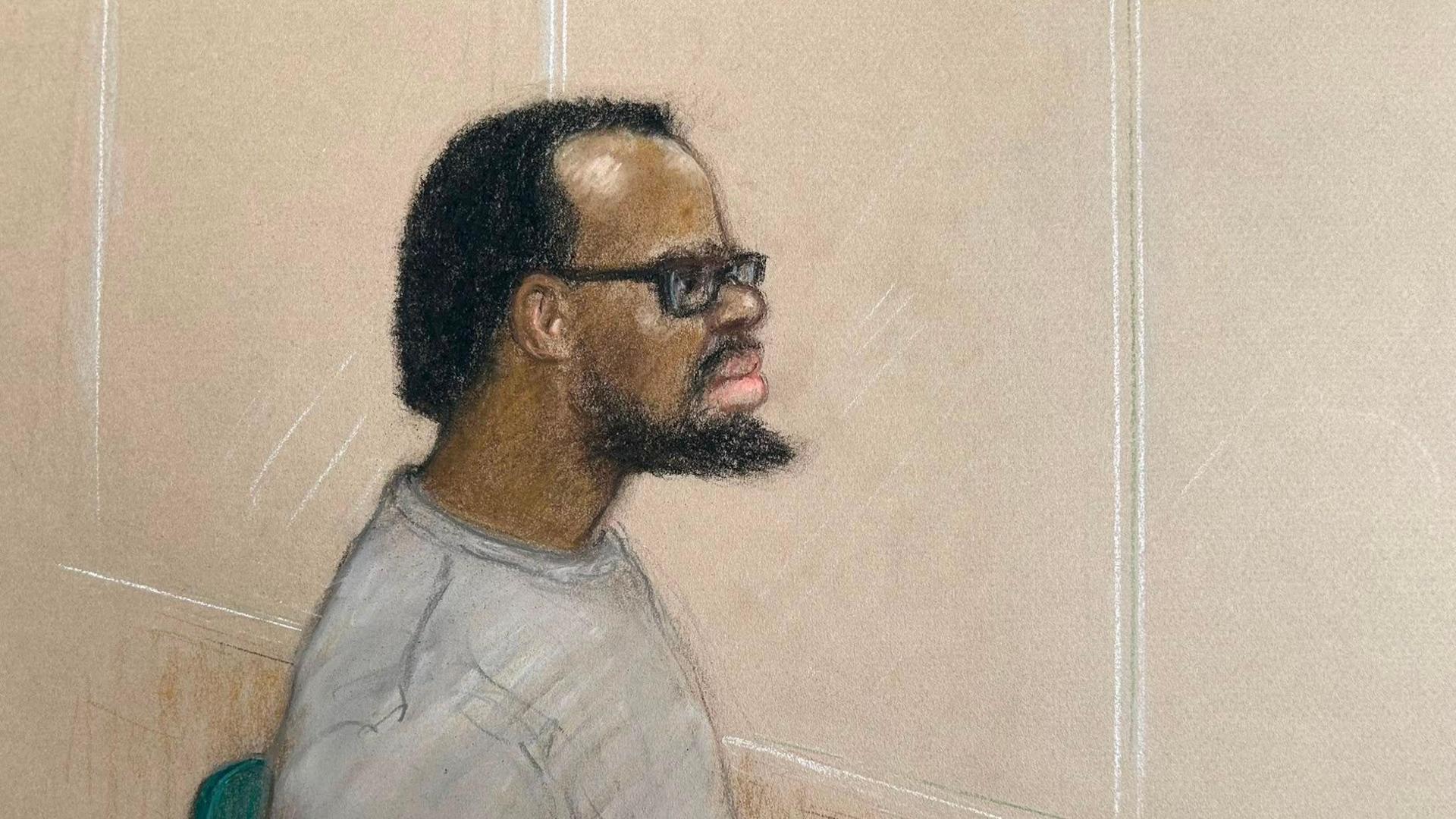 Court sketch of Simon Levy, wearing a long sleeved grey top and thick rimmed glasses. He has short dark hair which appears to be receding, and a beard.