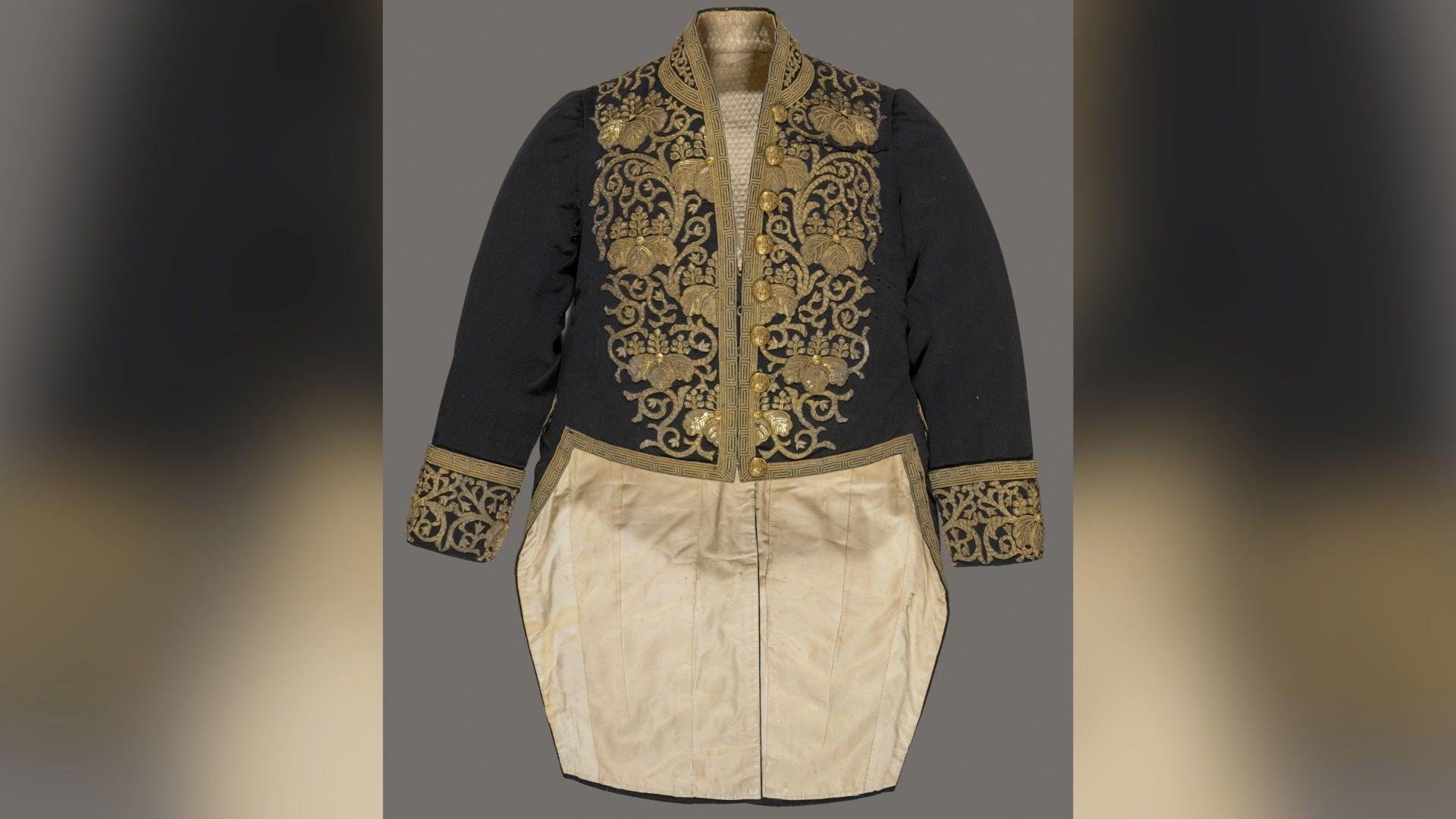 A black top half with gold embroidery and silky looking gold bottom half of what resembles a long suit jacket. 