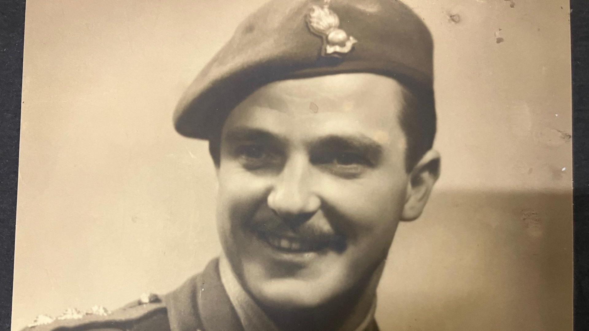 A black and white picture of a man with a moustache in a wartime military outfit 