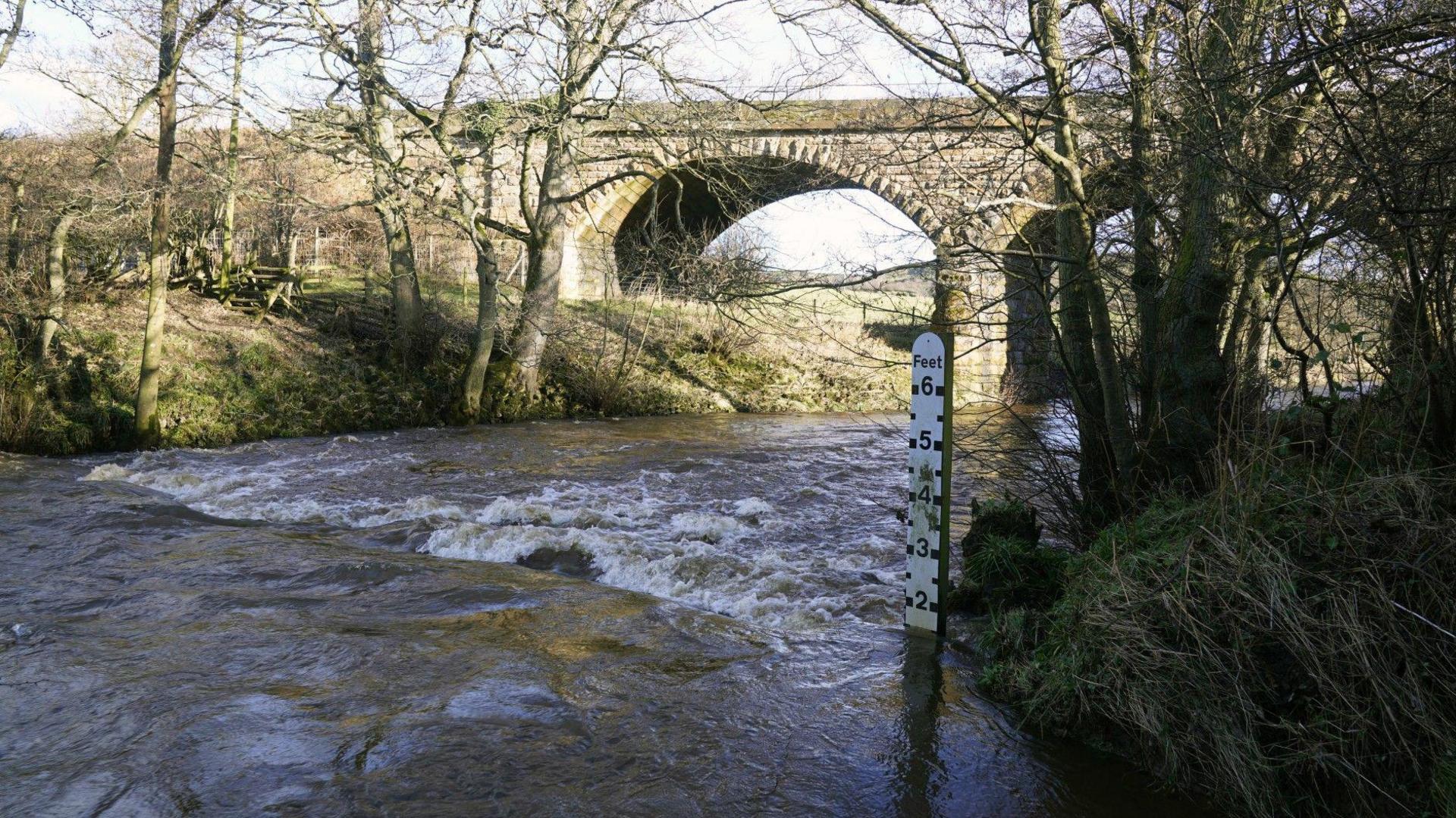 The River Esk near Glaisdale flows underneath a bridge, with a depth marker post on the right