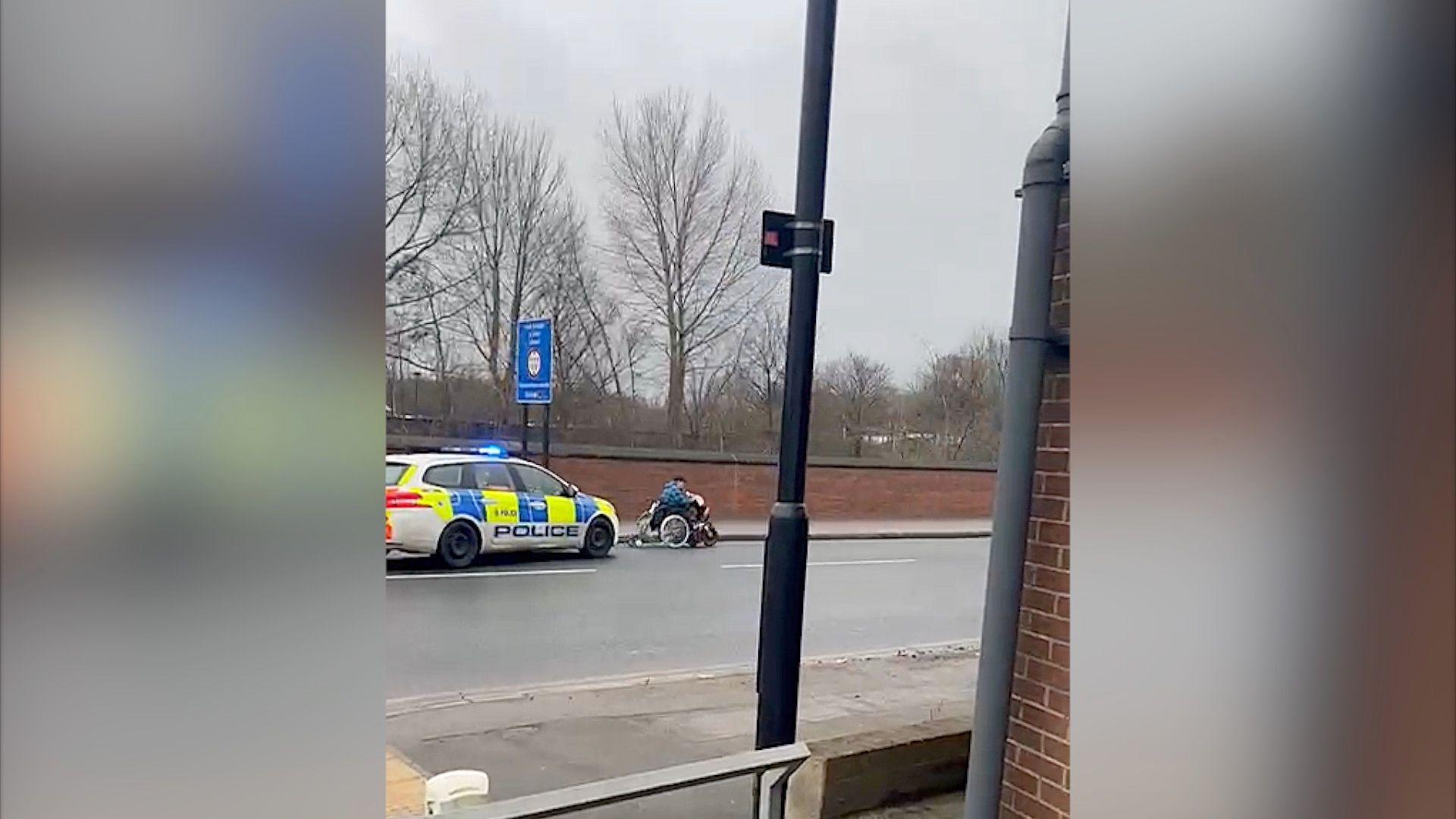 A police car chases a woman in a motorised wheelchair.