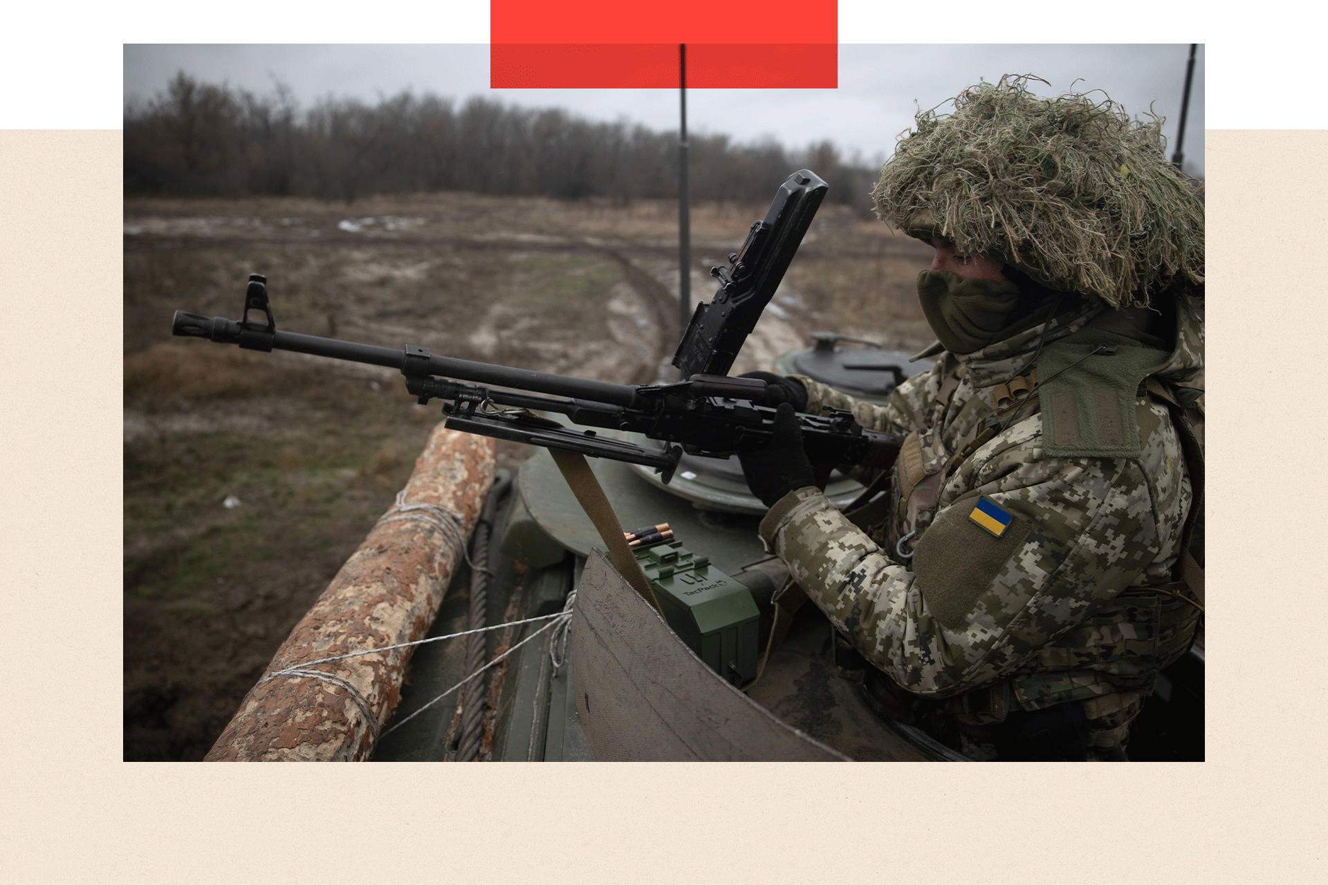 A close-up of a Ukrainian soldier inside a tank, holding a rifle at the ready