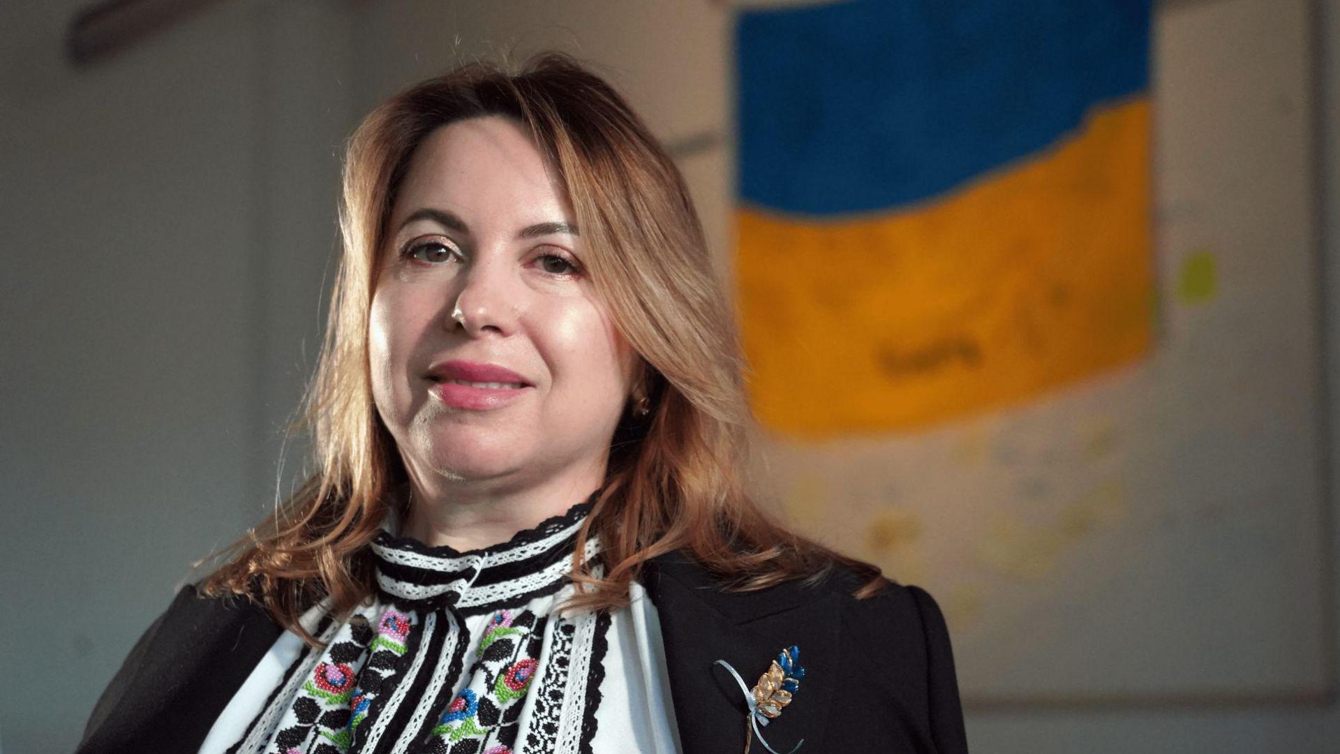 Nataliya Lyalyuk standing in front of a Ukrainian flag.