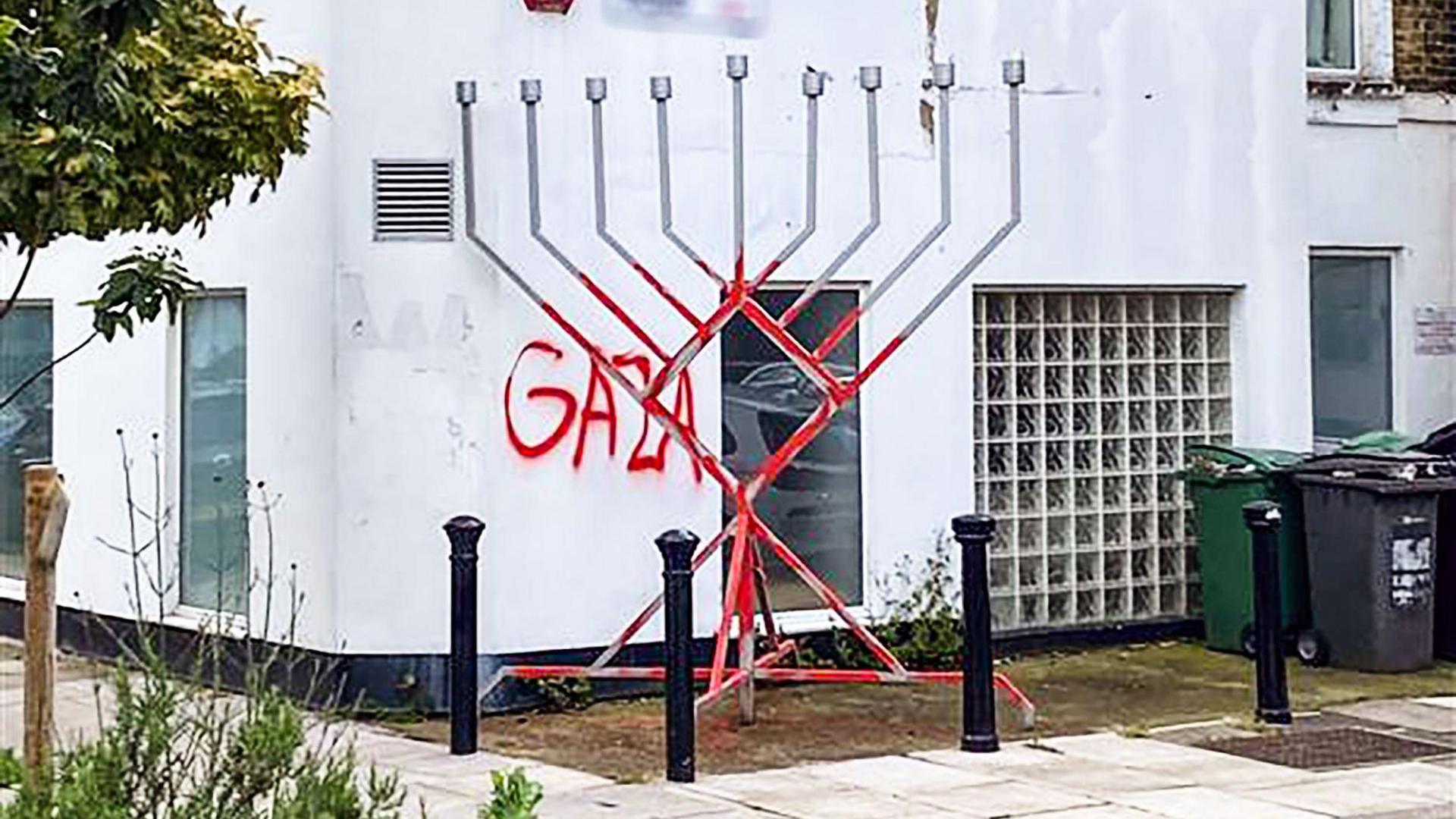 A menorah daubed in red paint and the word "Gaza" written on a wall behind