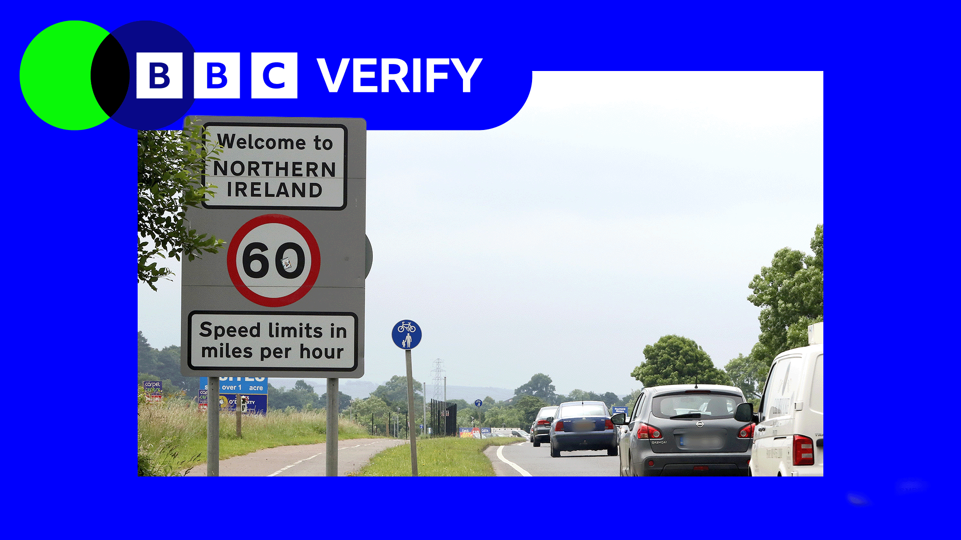 Cars drive towards a sign reading "Welcome to Northern Ireland". 