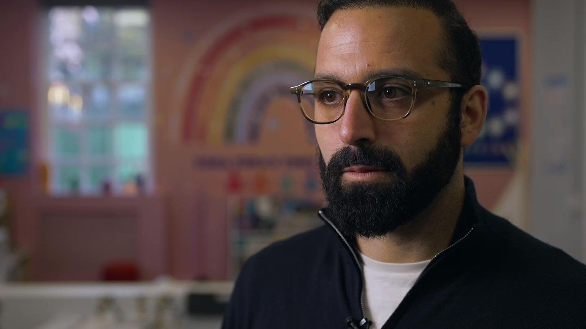 A man with glasses and a beard is pictured in a childcare setting
