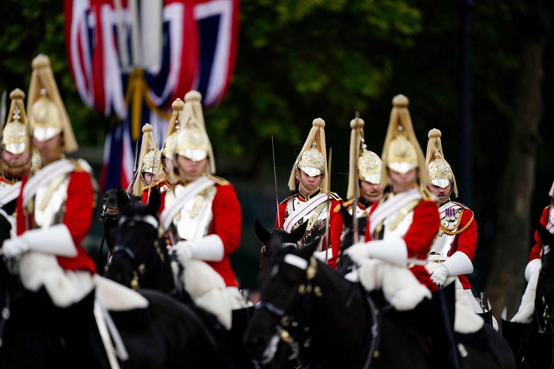 Horseback military personnel wearing red uniforms and gold headwear march down the Mall.