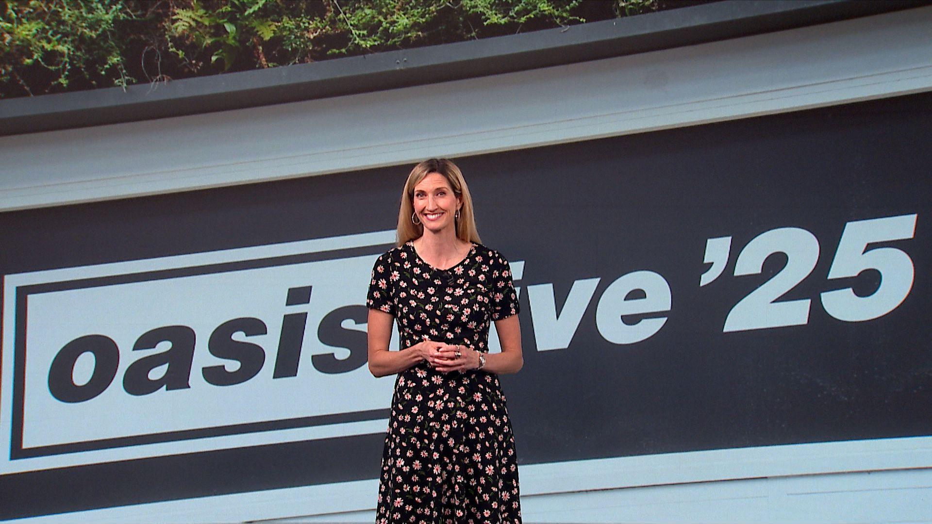 Joy Dunlop stands in front of a black and white backdrop of Oasis live '25