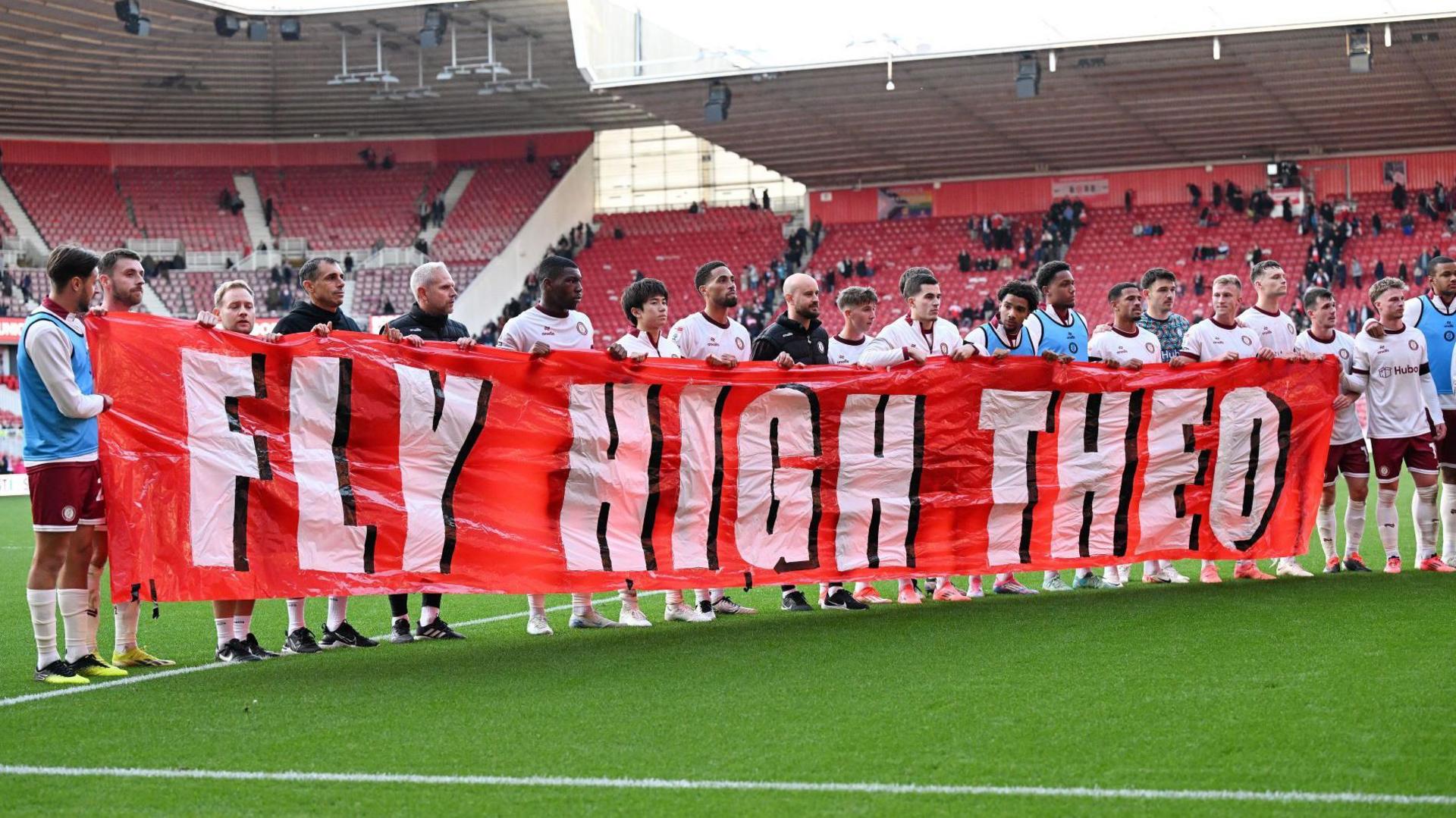 Bristol City's players hold a banner in tribute to Theo John Manning before kick off against Middlesbrough 