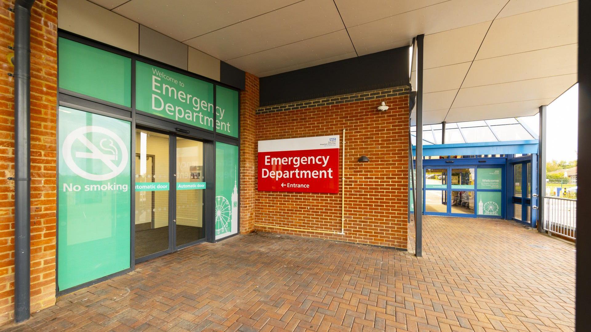 An entrance to a bricked building. There is a green doorway and a red sign. 