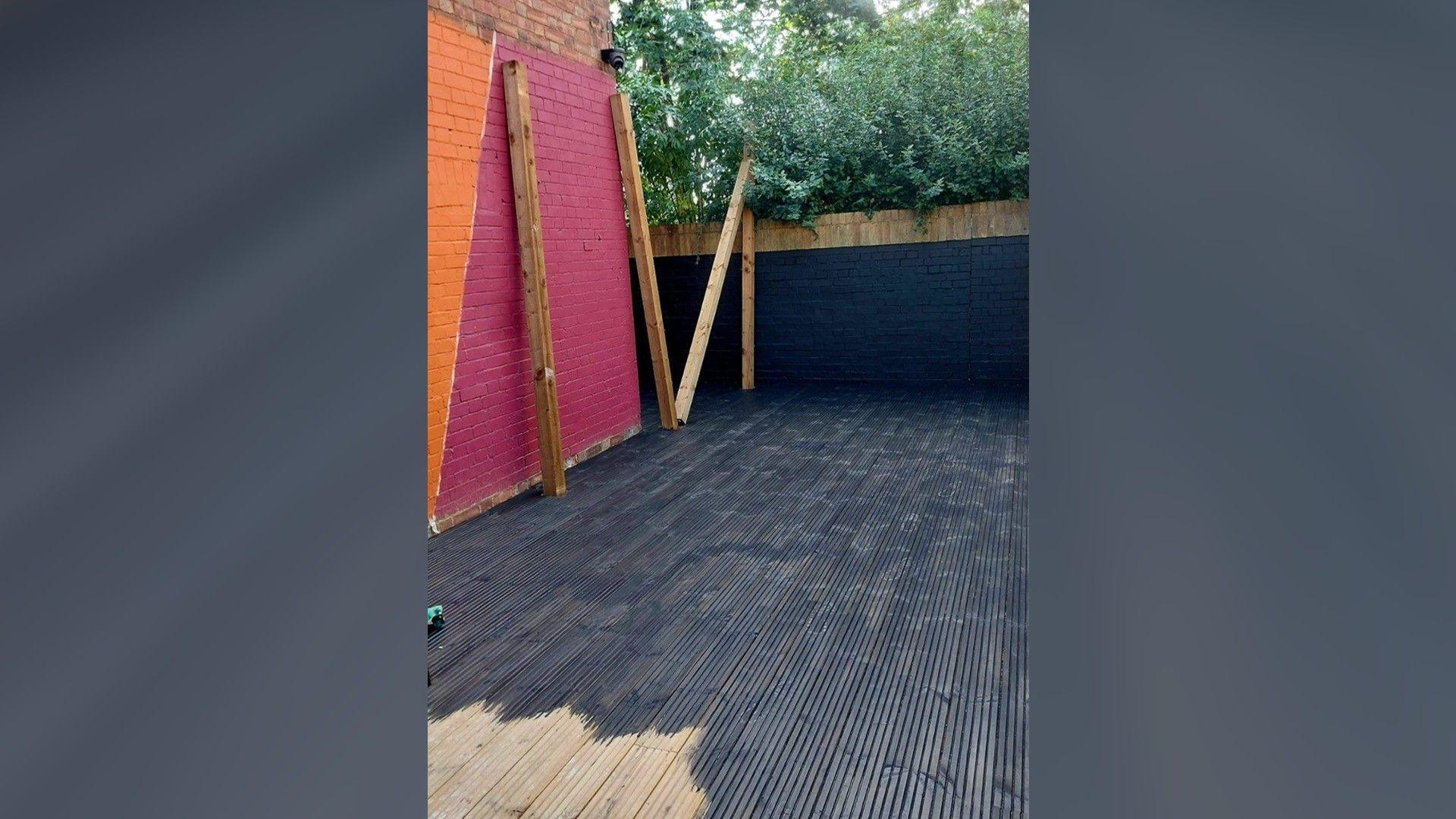 A deck with black floor with pink and orange paint on the wall 