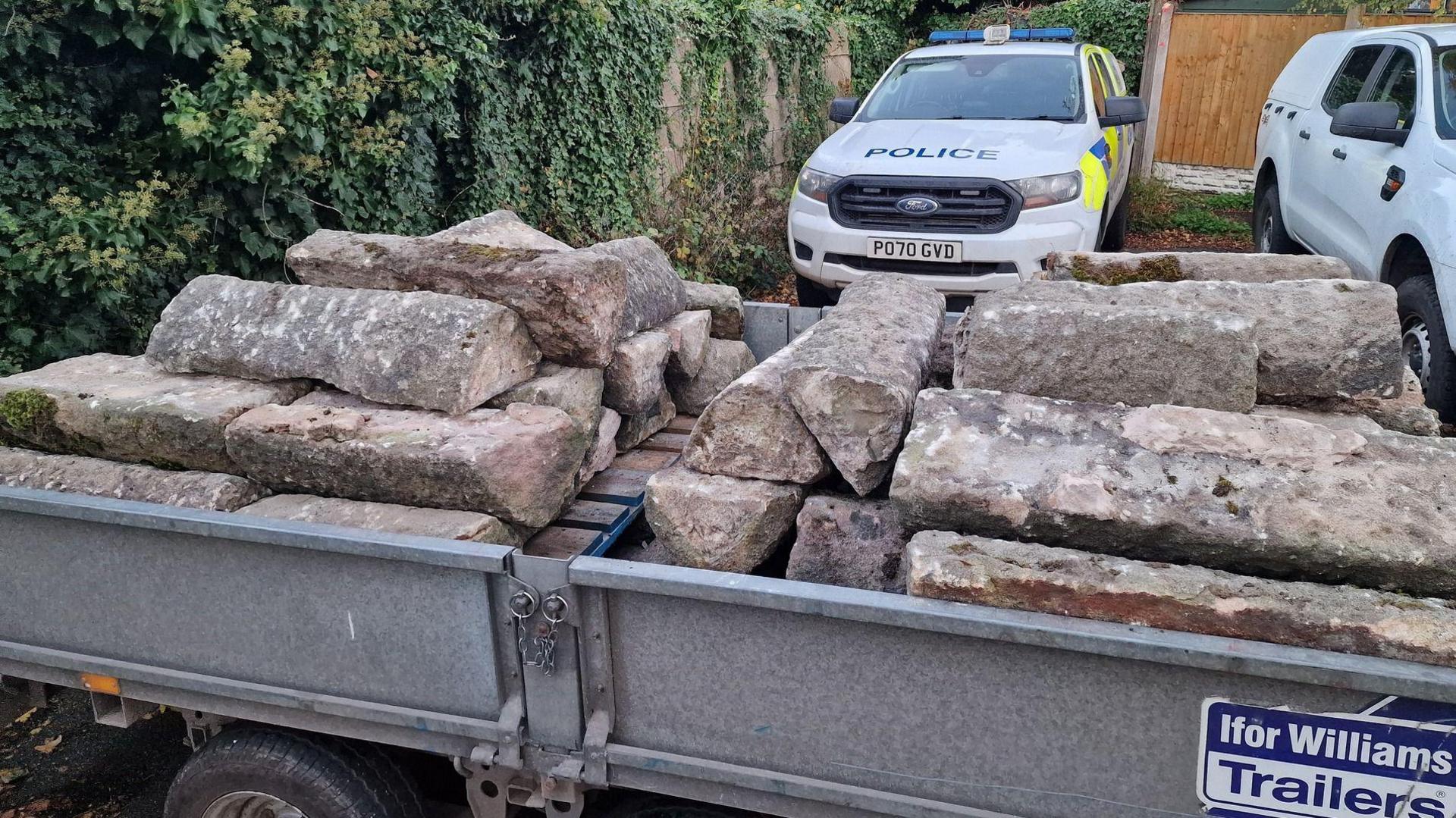 A trailer with slabs is in front of a police car