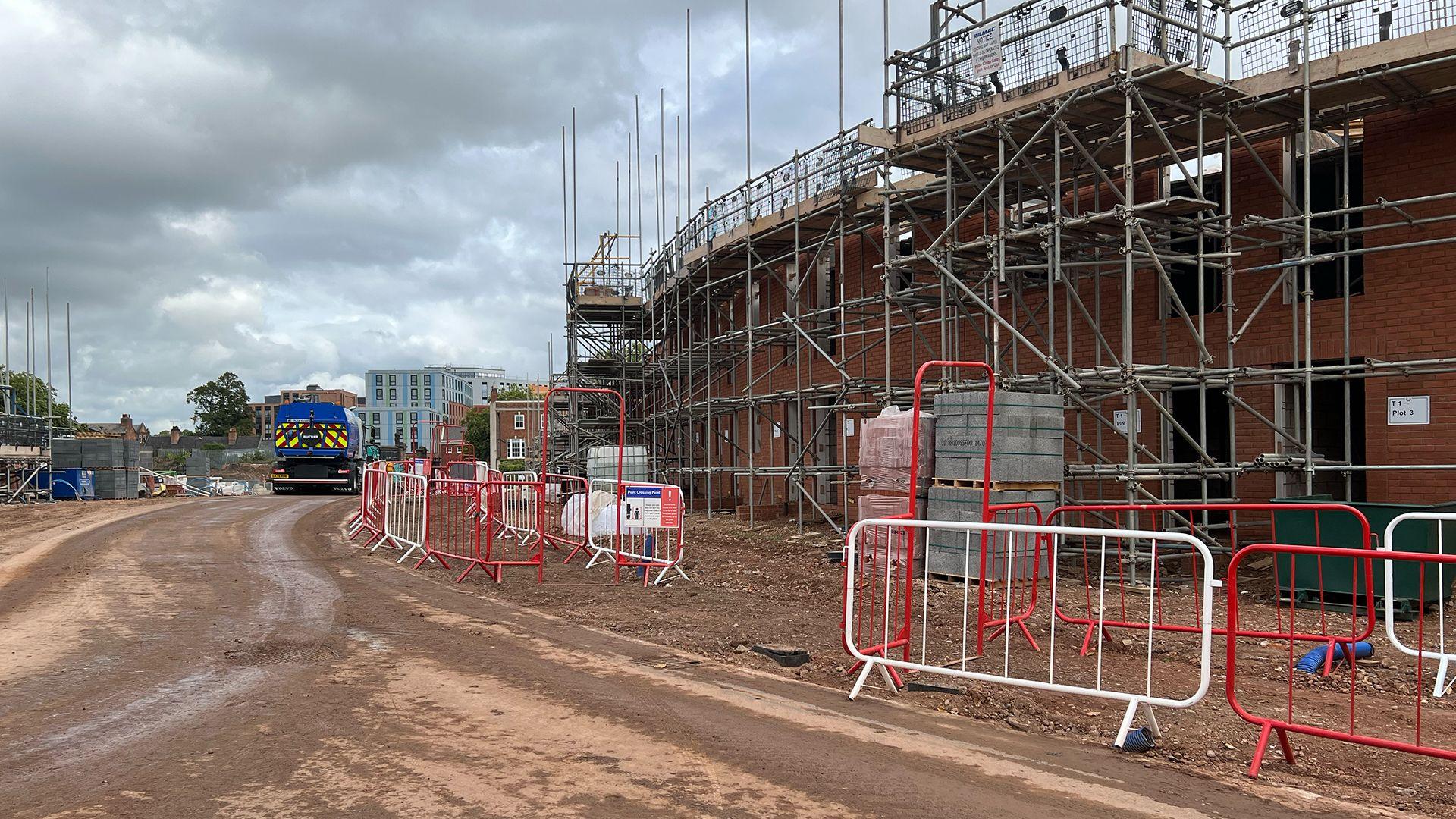 A construction site in Derby showing a spine road on the Friar Gate Goods Yard site next to a block of terraced houses with a slight curve.