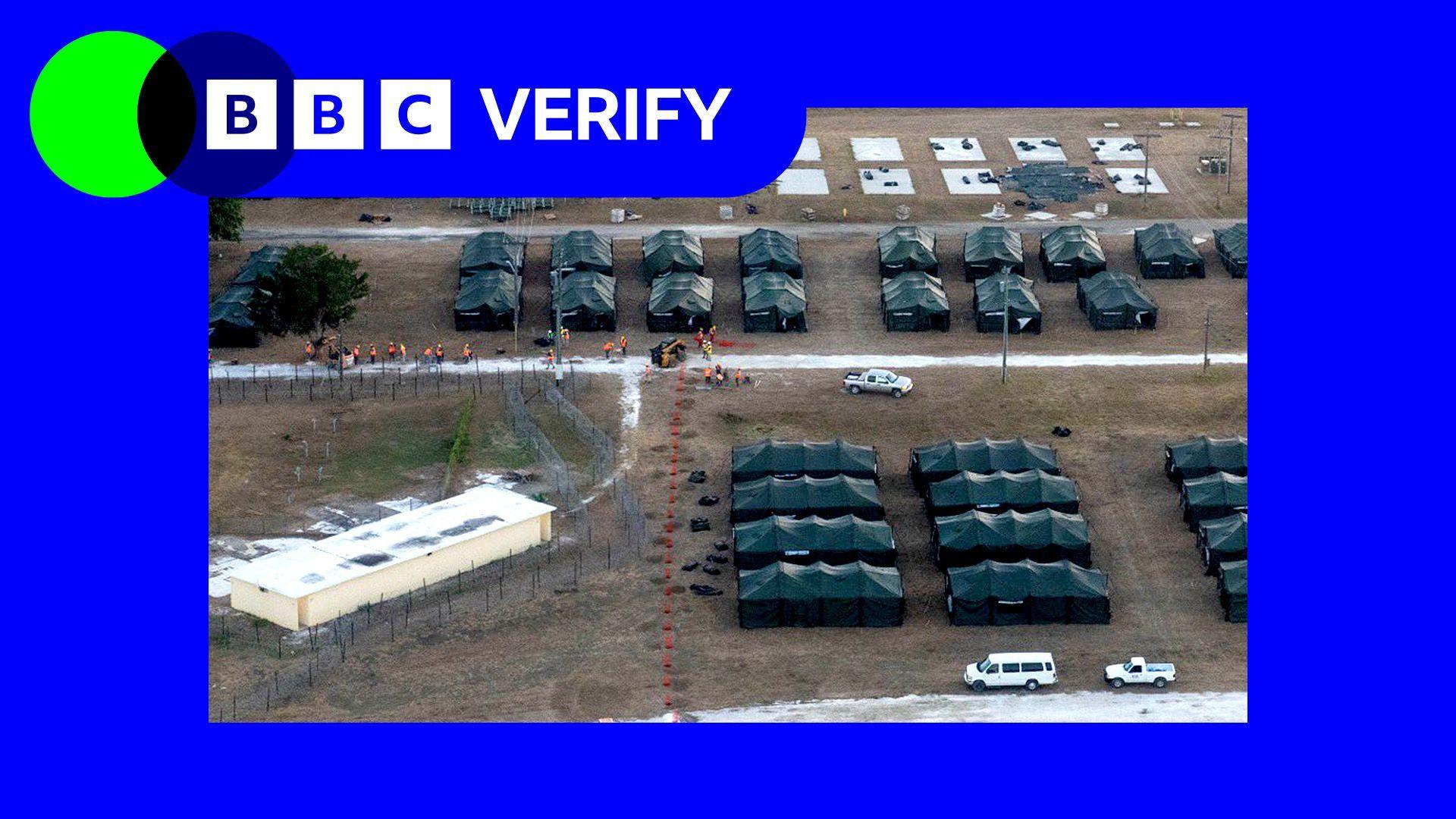 An image of tents at the Guantanamo migrant camp posted by US Homeland Security Secretary Kriti Noem. Banks of tents are visible with some vehicles. The BB Verify logo and colours have been imposed over it.