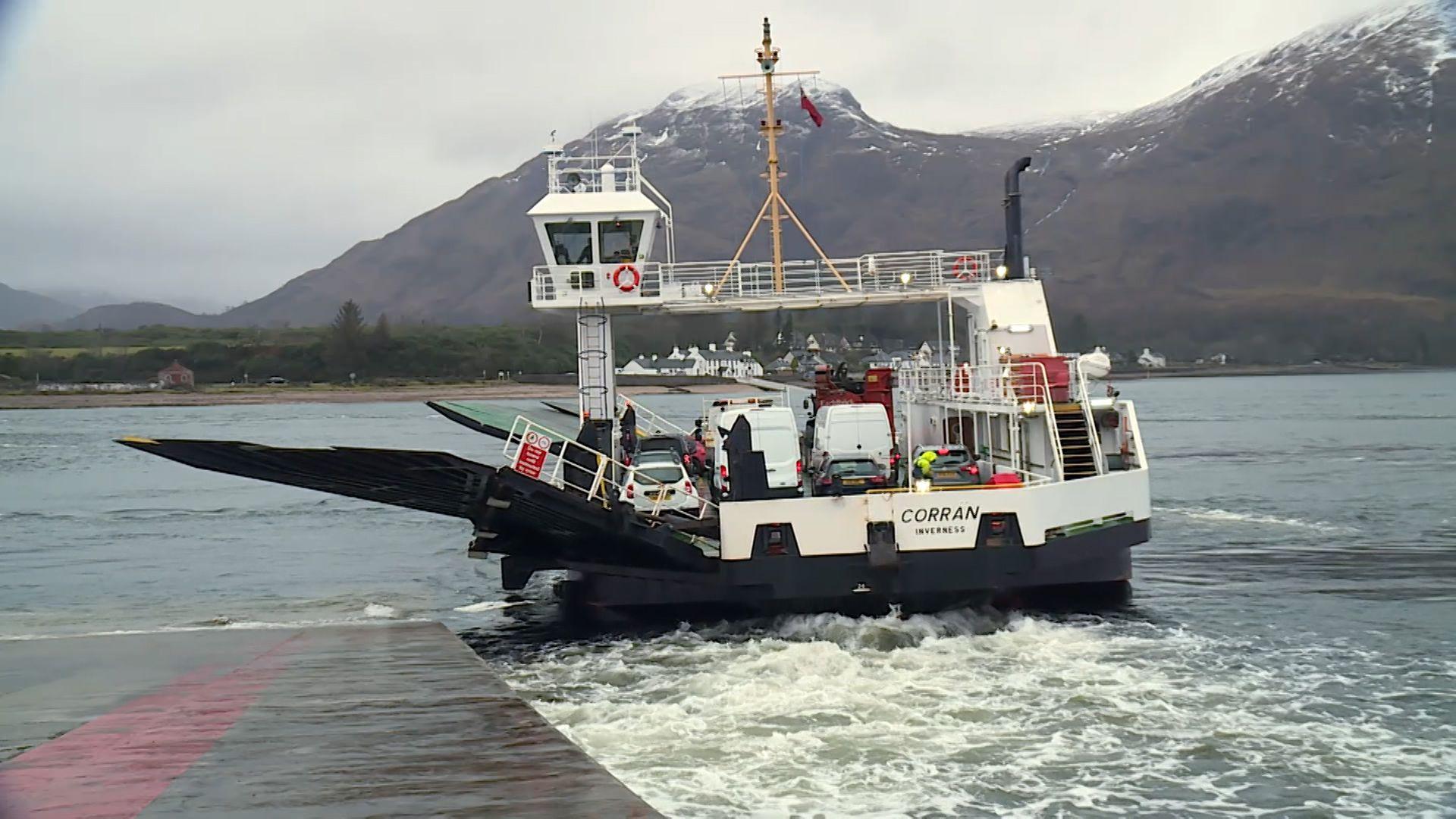 MV Corran car ferry with cars on board departs to cross the Corran Narrows in Lochaber near Fort William on a cloudy say with snow-capped mountains in the distance