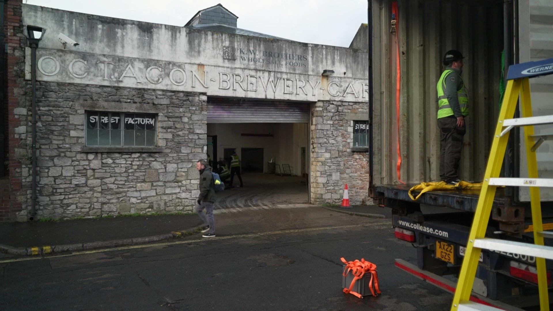 A grey building that says Octagon Brewery and a lorry with a man in the back of it