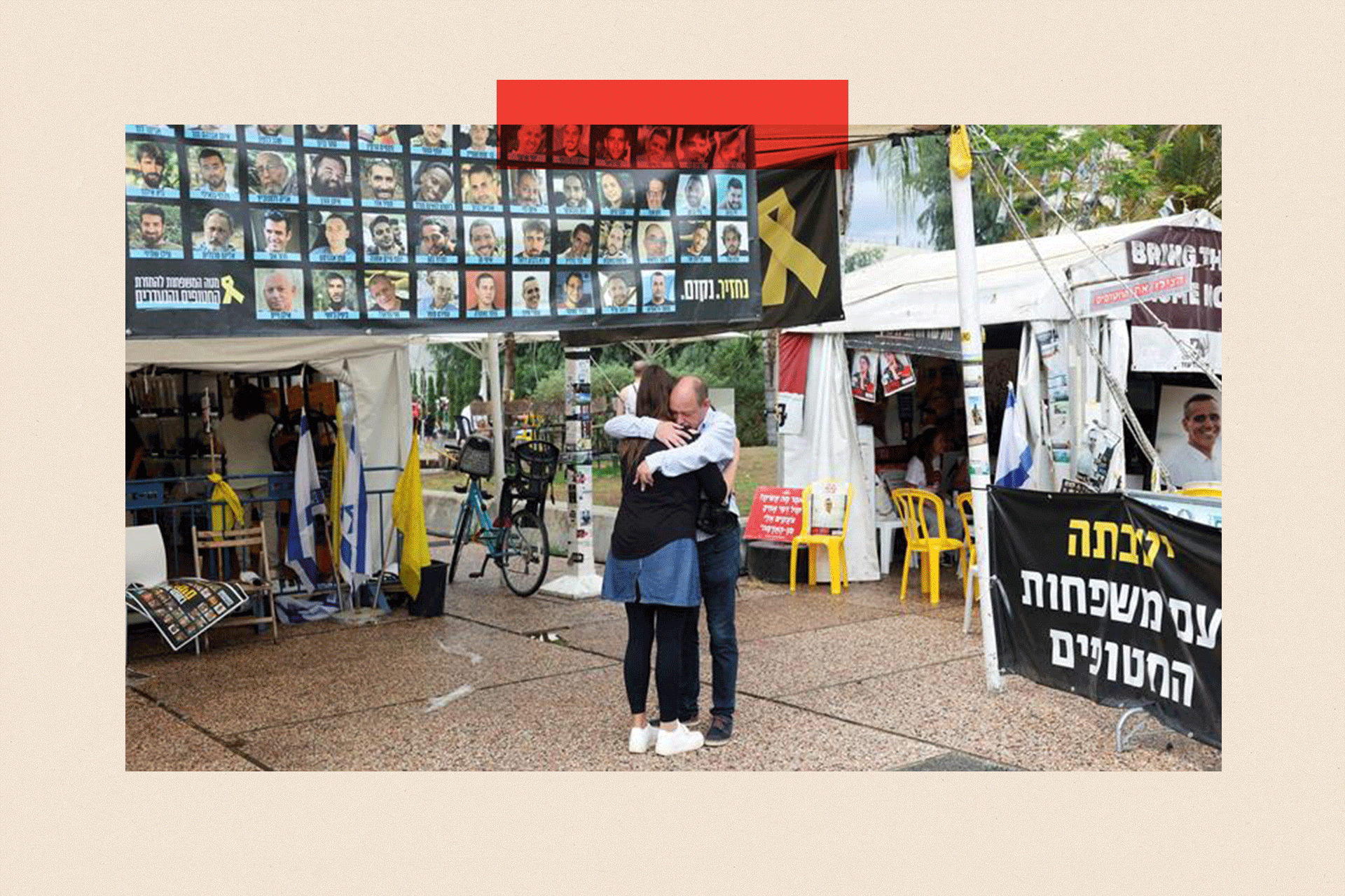 People hug next to banner with photos of hostages