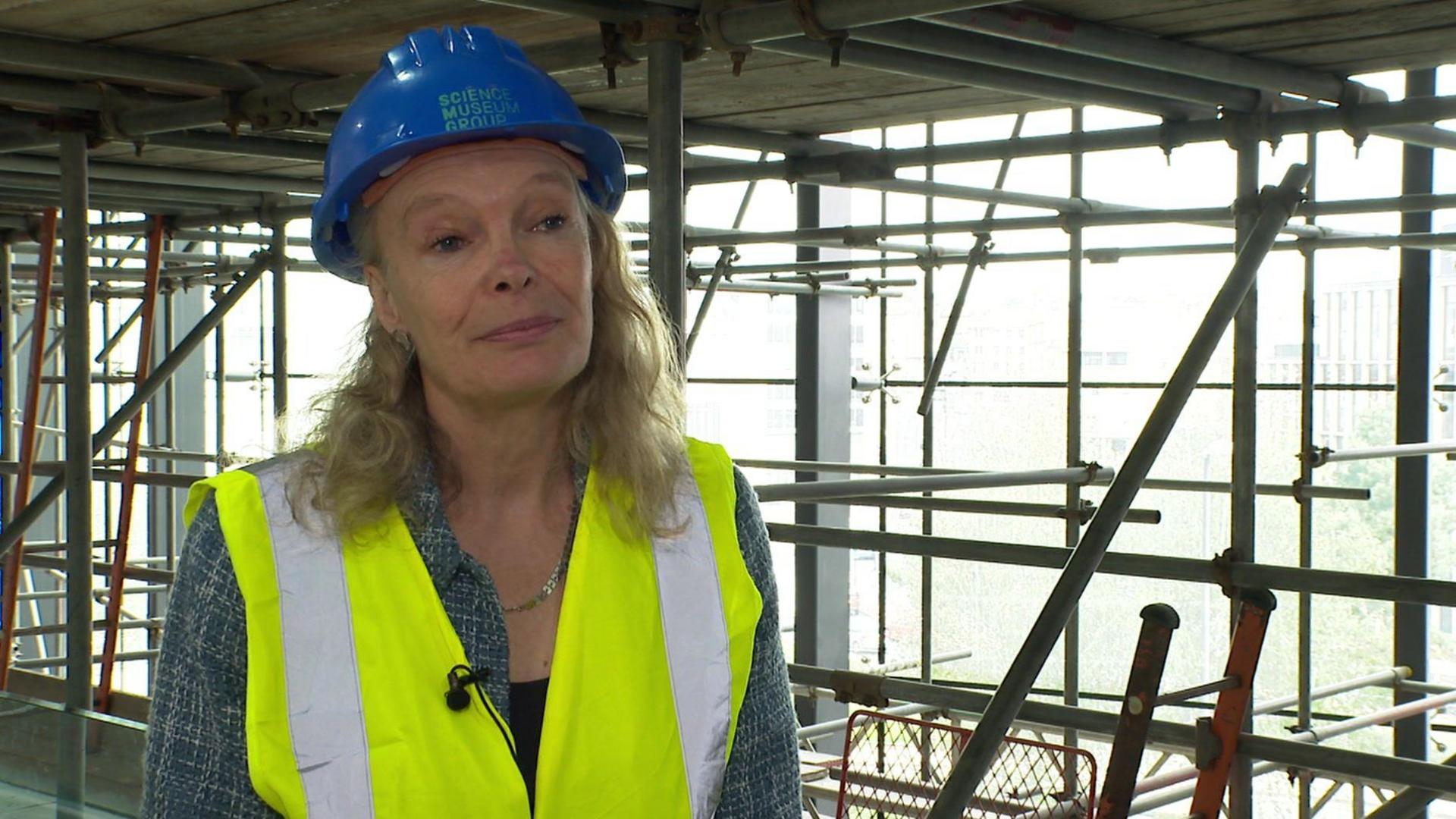 Museum director Jo Quinton-Tulloch wears a hard hat while standing in the building site area of the museum