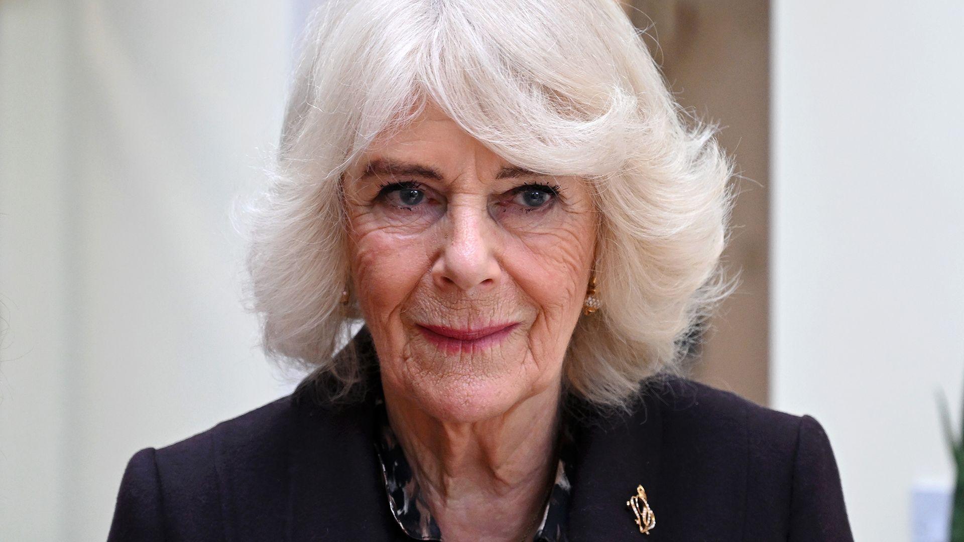 Queen Camilla looks away from camera while wearing a black suit jacket, pictured in London in February.