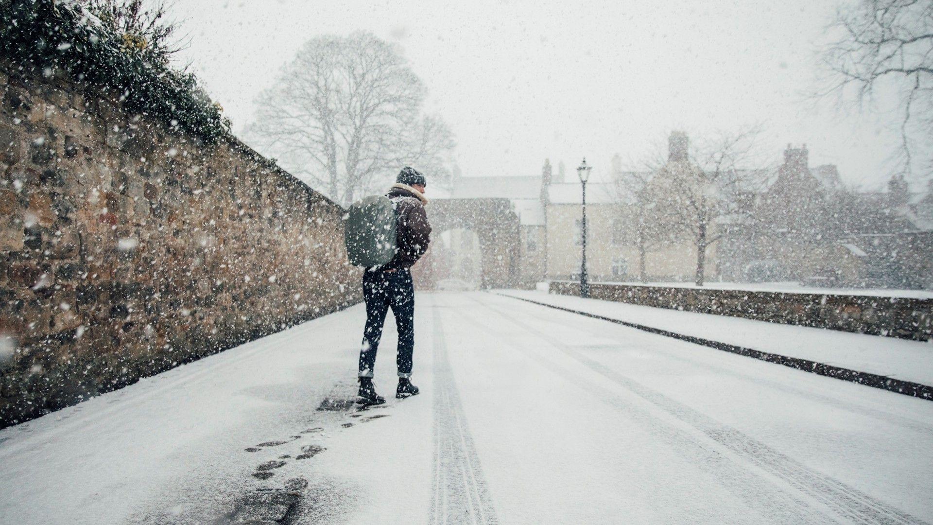 Man walks along a snow covered street with a rucksack on his back 
