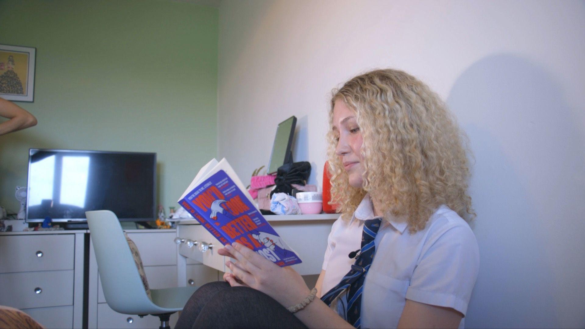 Violet reading a book in her room