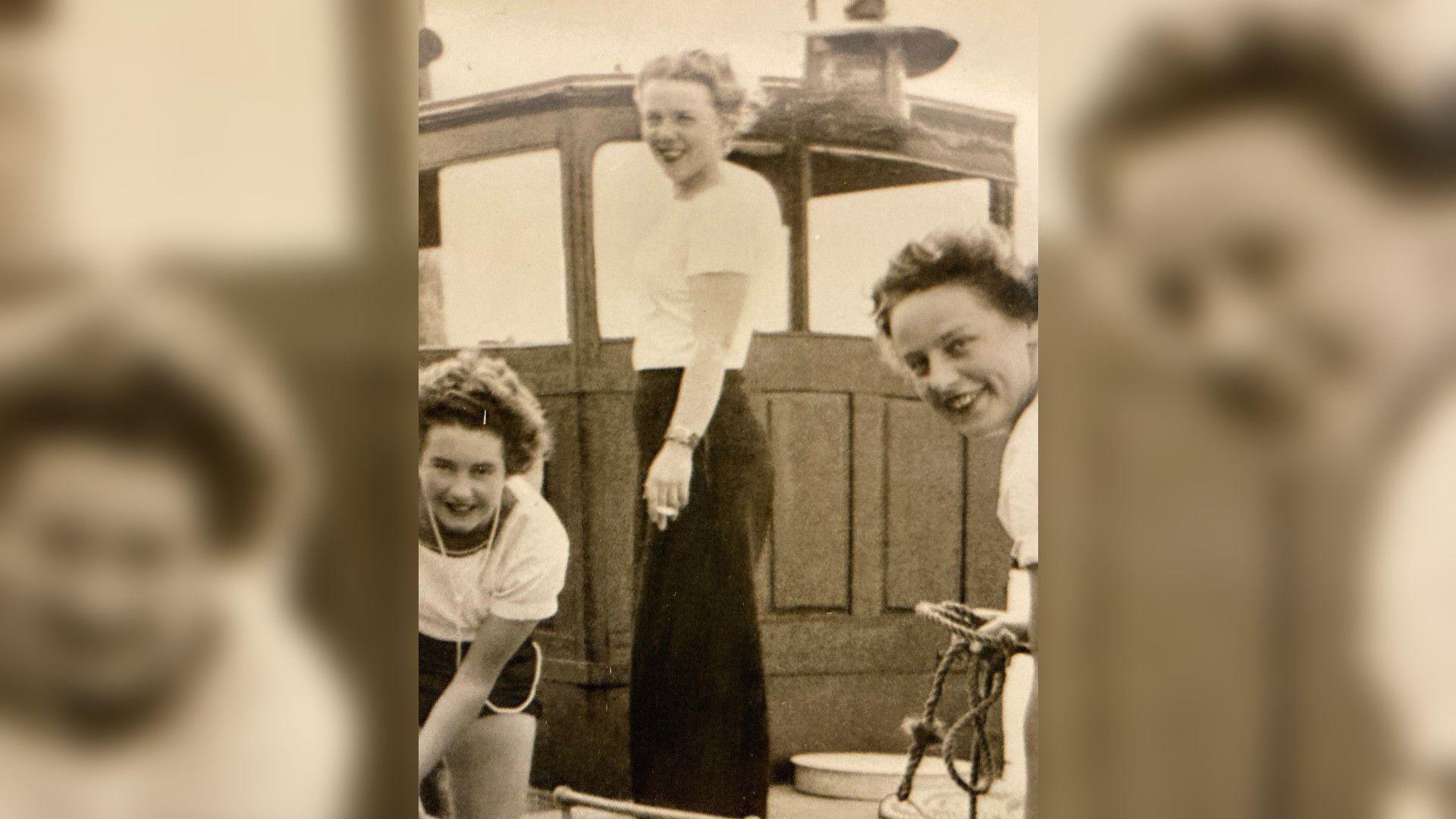 A black and white picture shows three Wrens on Beaulieu River, near HMS Mastodon. The three white women are looking at the camera and smiling