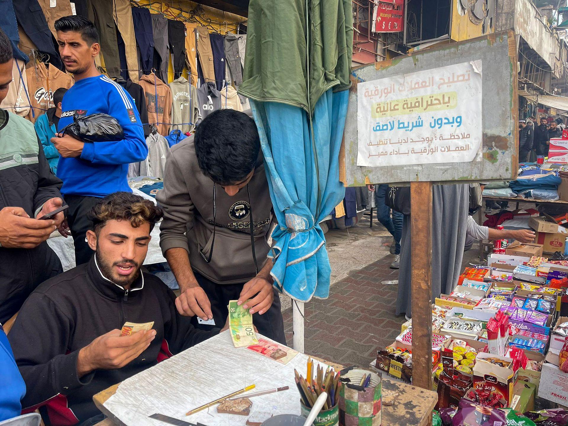 Baraa Abu al-Aoun repairing banknotes at a market in Gaza City