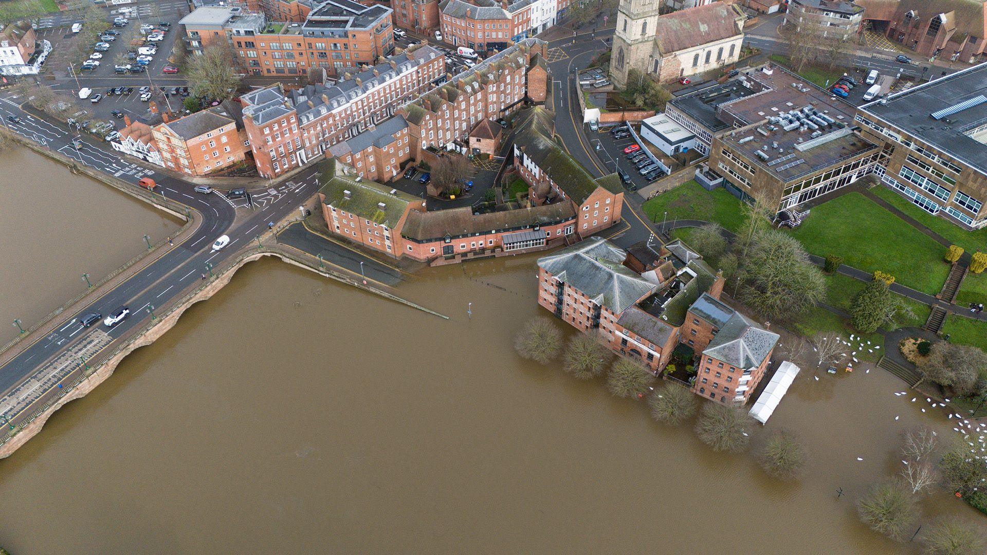 An aerial view shows the town of Worcester submerged in floodwater with cars driving along a bridge on 9 February.